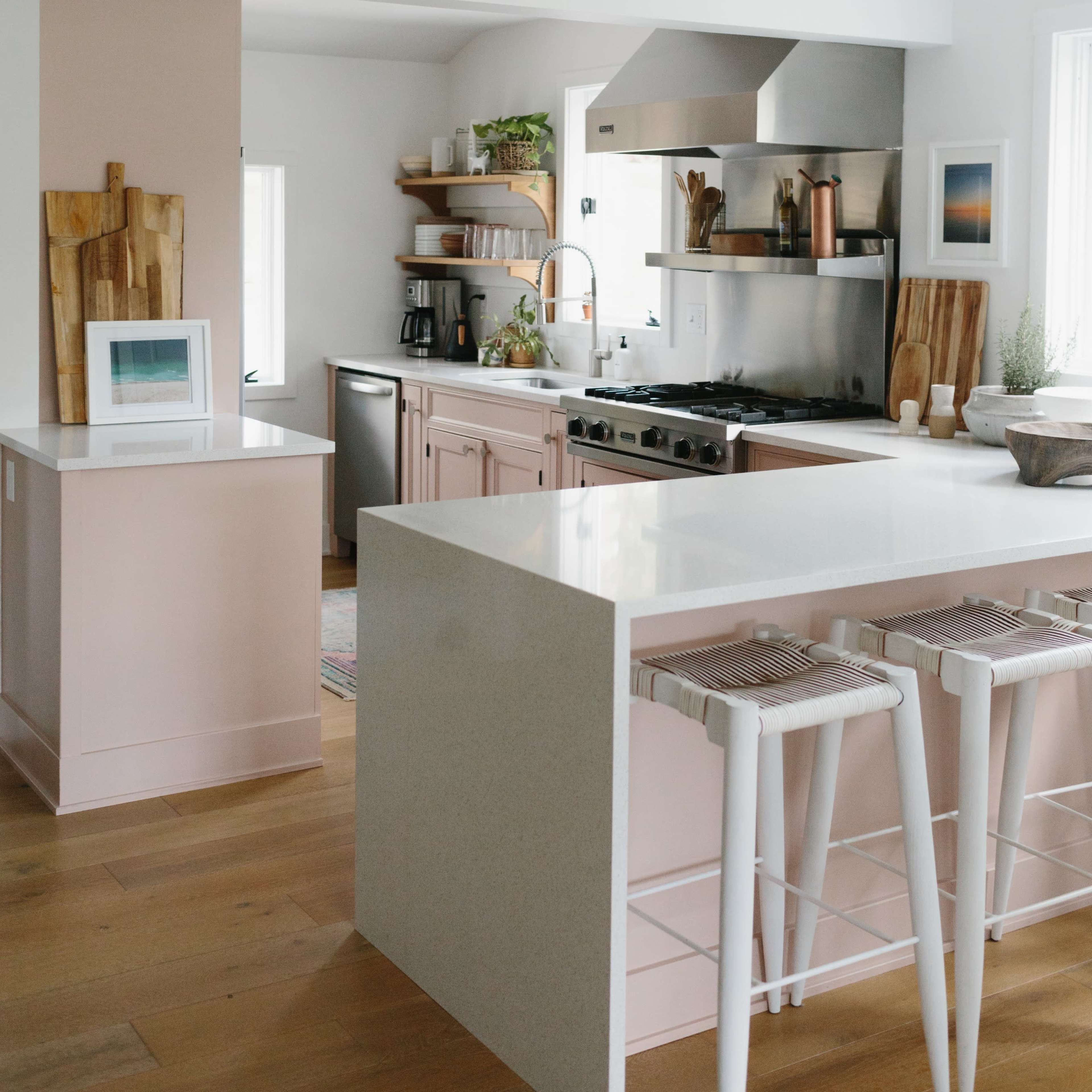 A modern kitchen with a central island, stainless steel appliances, and light-colored cabinetry.