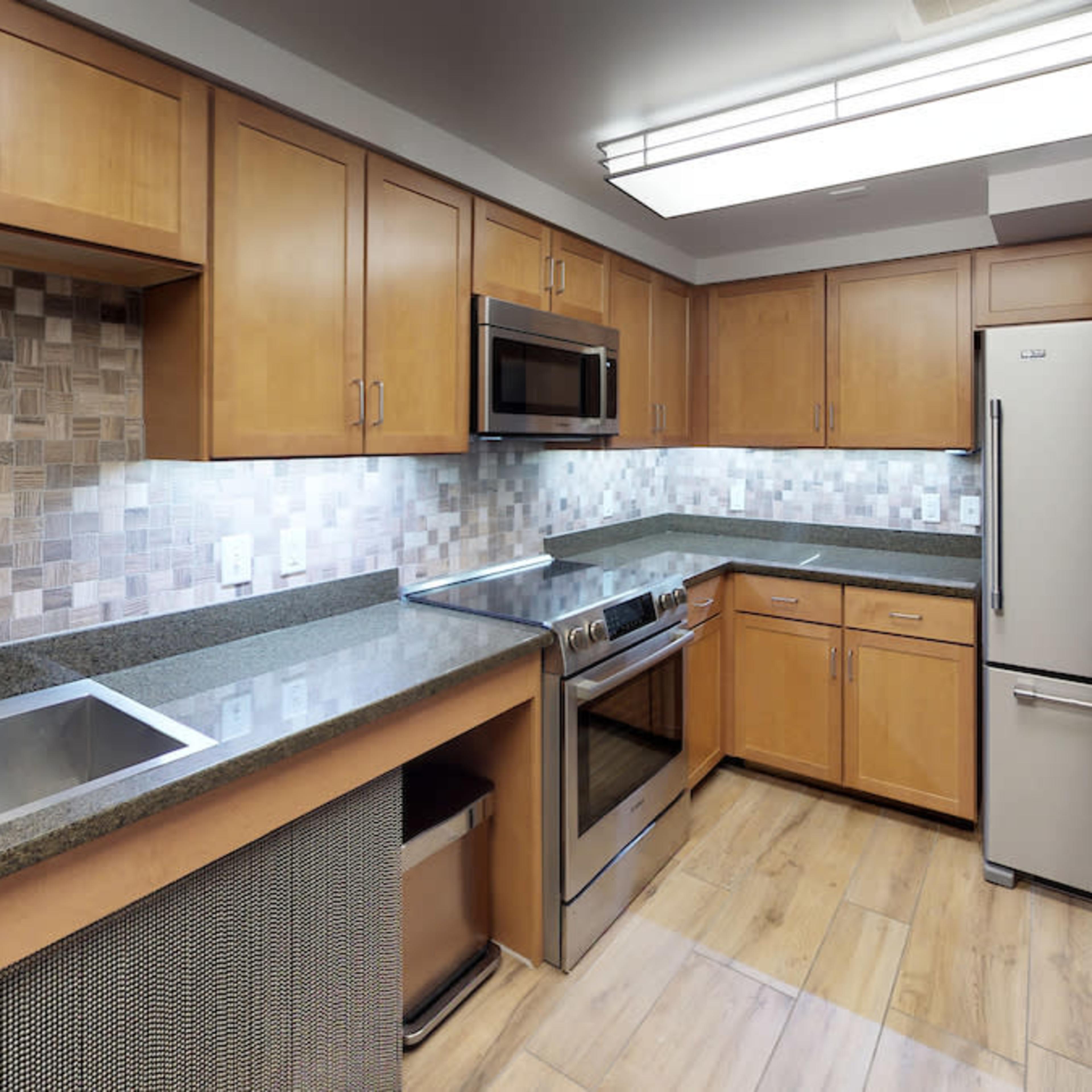 A modern kitchen featuring wooden cabinets, stainless steel appliances, and a tiled backsplash with a spacious countertop.