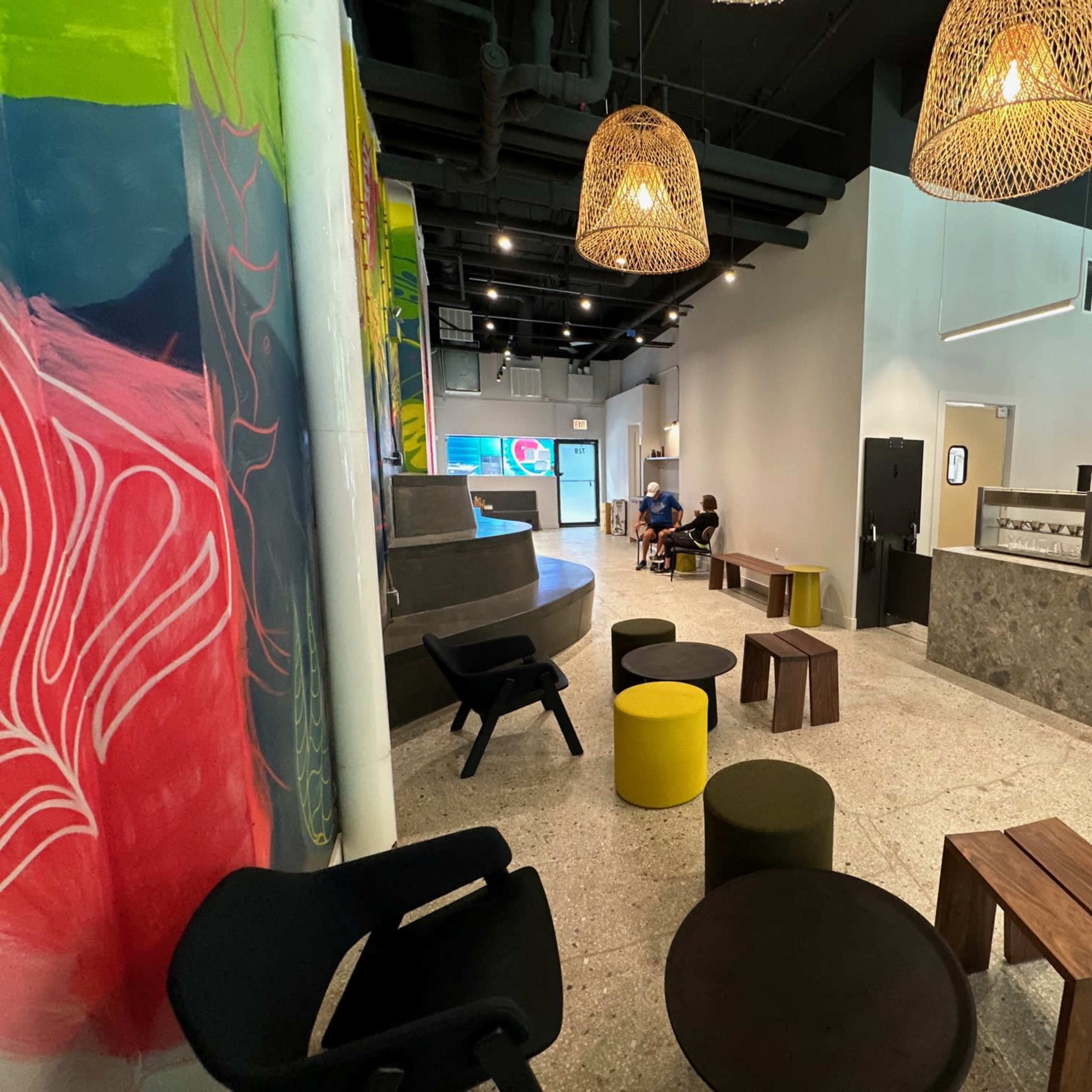 A modern indoor space with colorful wall art, various seating arrangements, and a service counter.