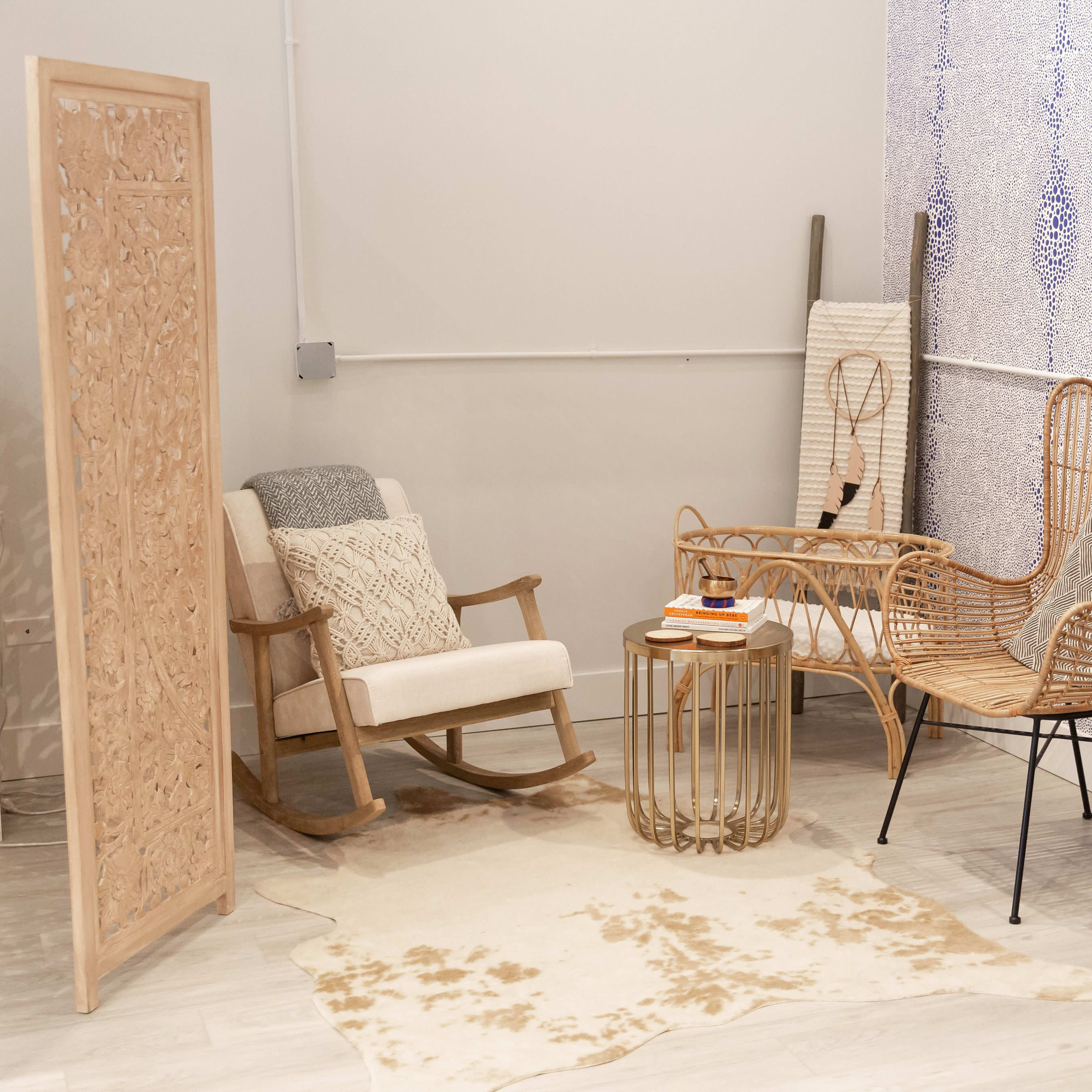 The scene features a cozy corner with a rocking chair, a rattan chair, a round glass table, and a decorative screen, all arranged on a patterned rug.