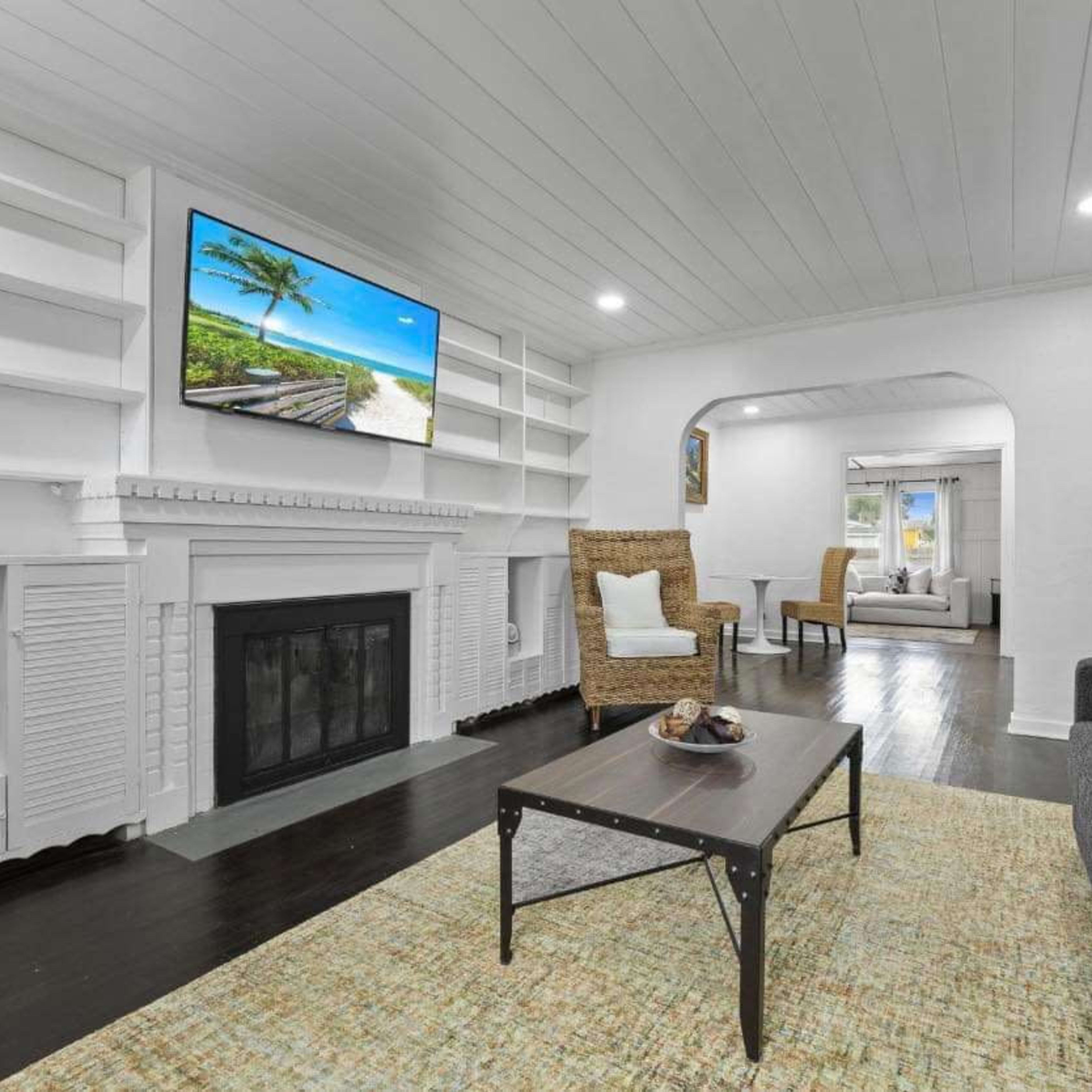 A living room with a sofa, a coffee table, a fireplace, and a large TV mounted on the wall, surrounded by built-in shelves.