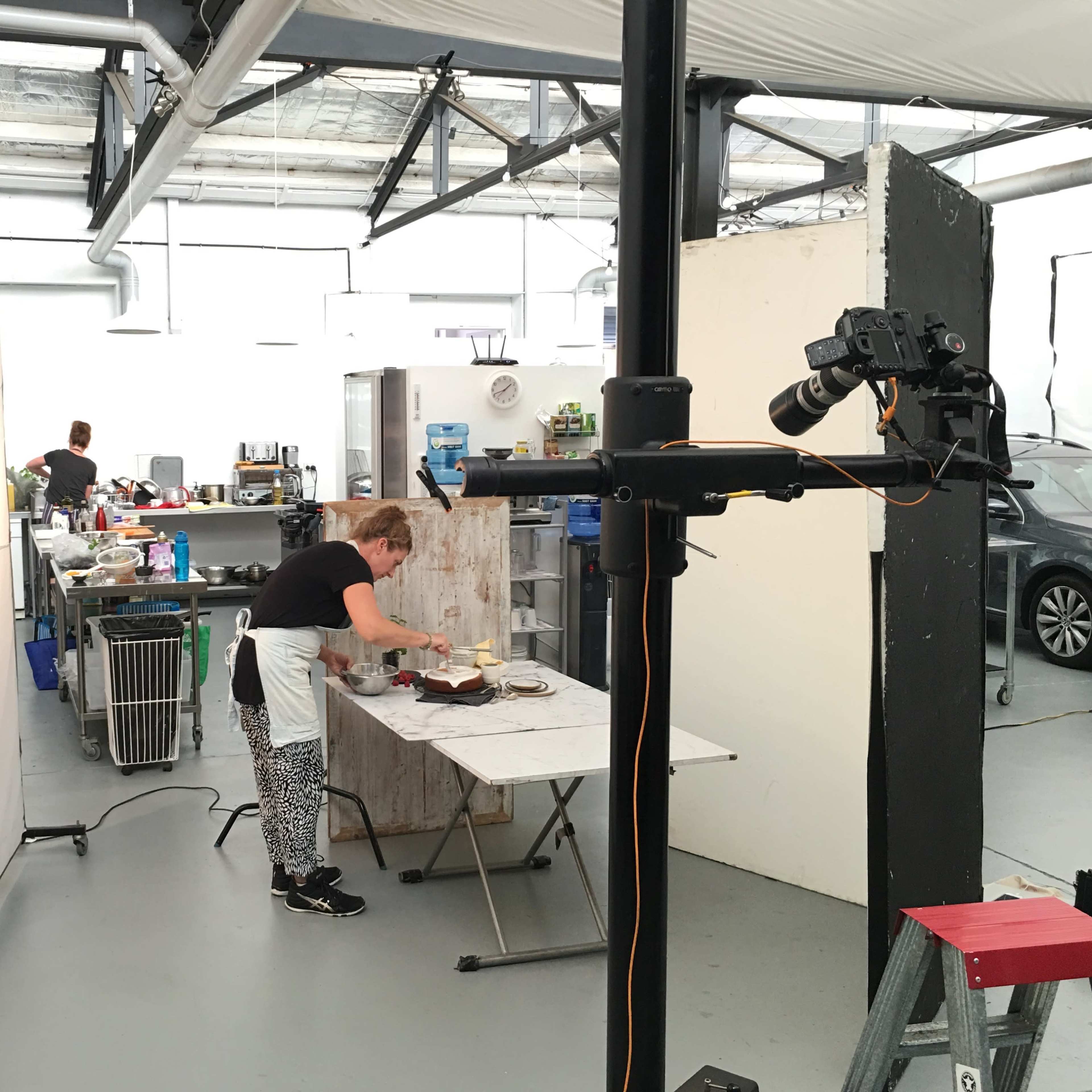 A woman prepares food at a kitchen table in a spacious industrial-style kitchen studio.