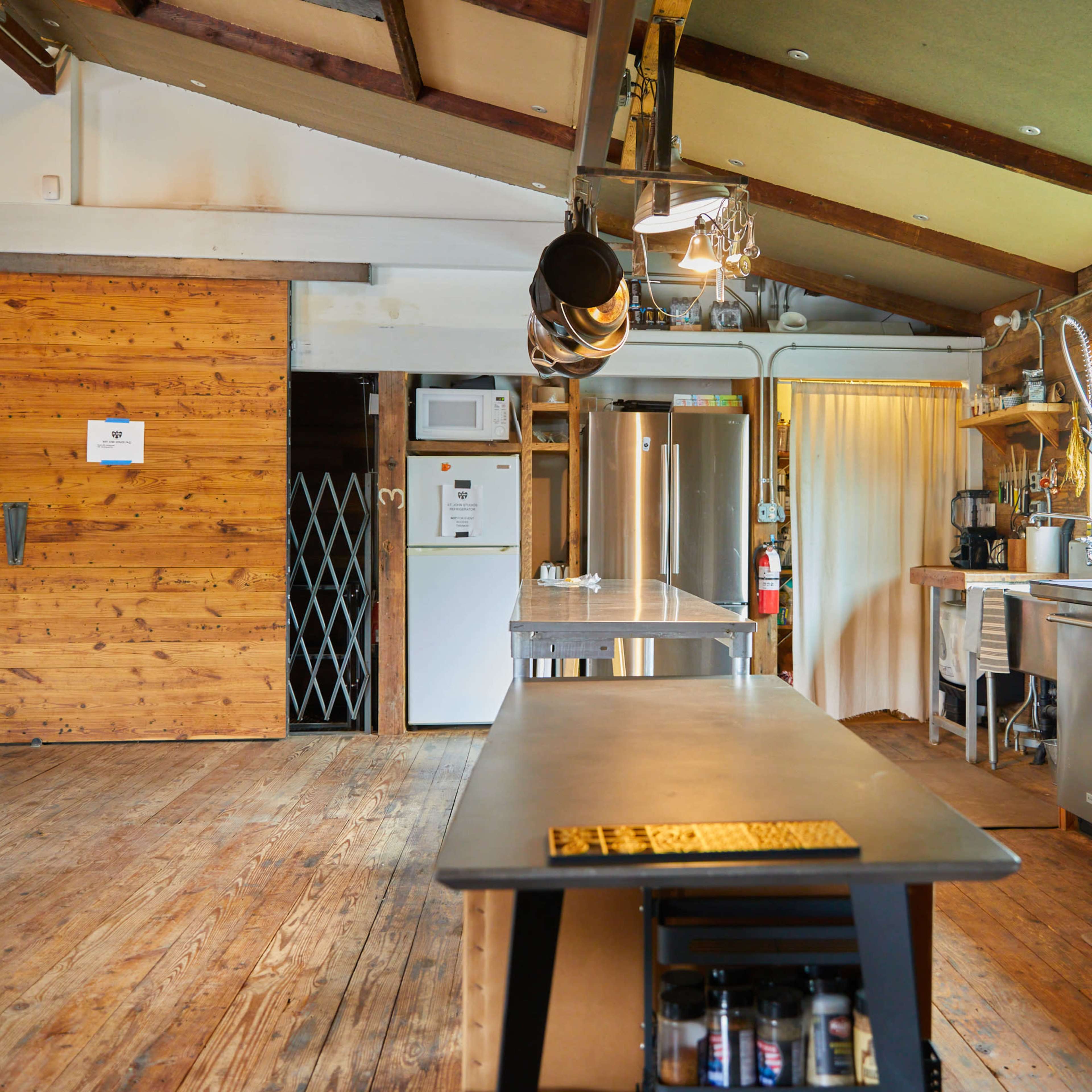 A spacious kitchen with wooden walls, a central island, and stainless steel appliances.