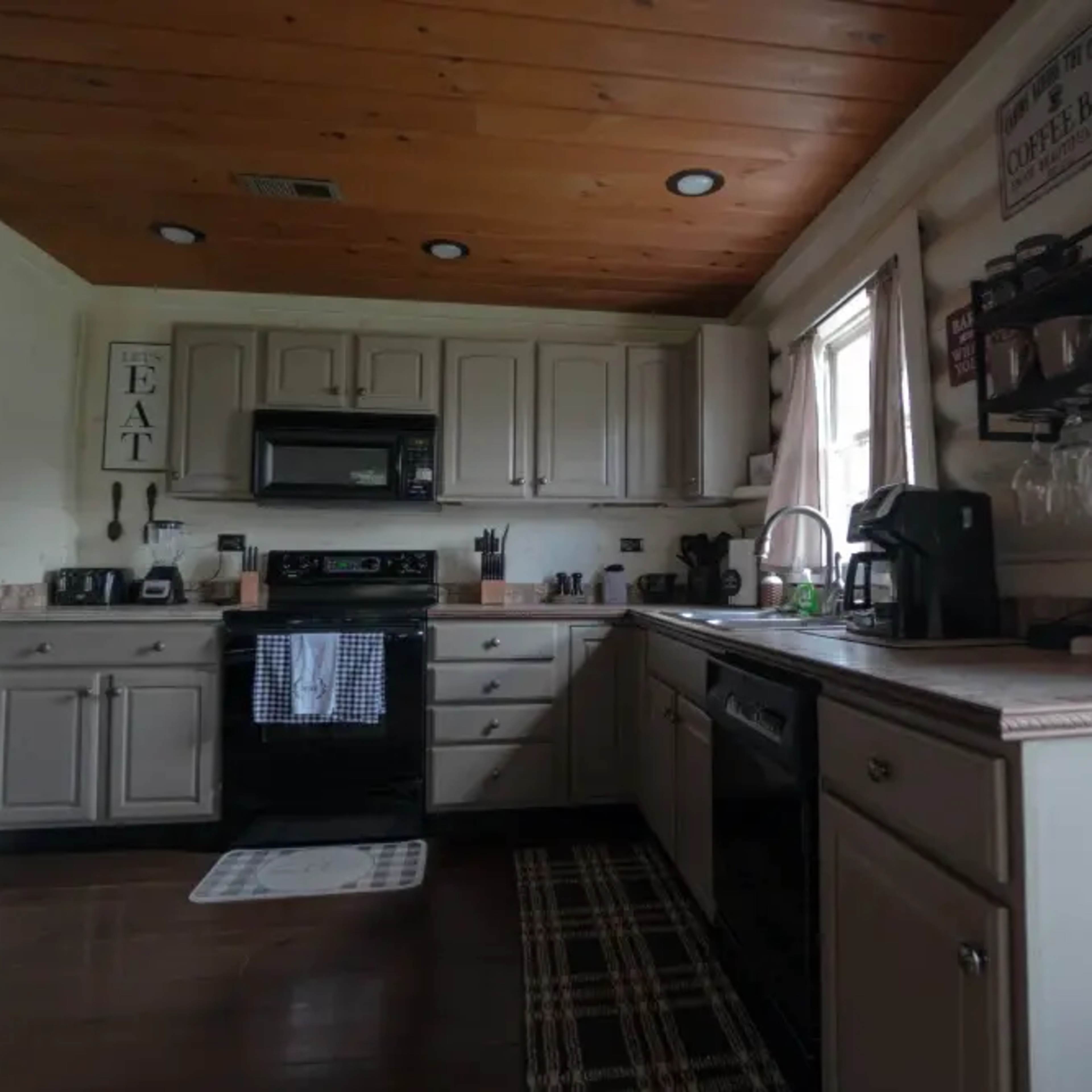 The kitchen features beige cabinets, stainless steel appliances, and a wooden ceiling with recessed lighting.