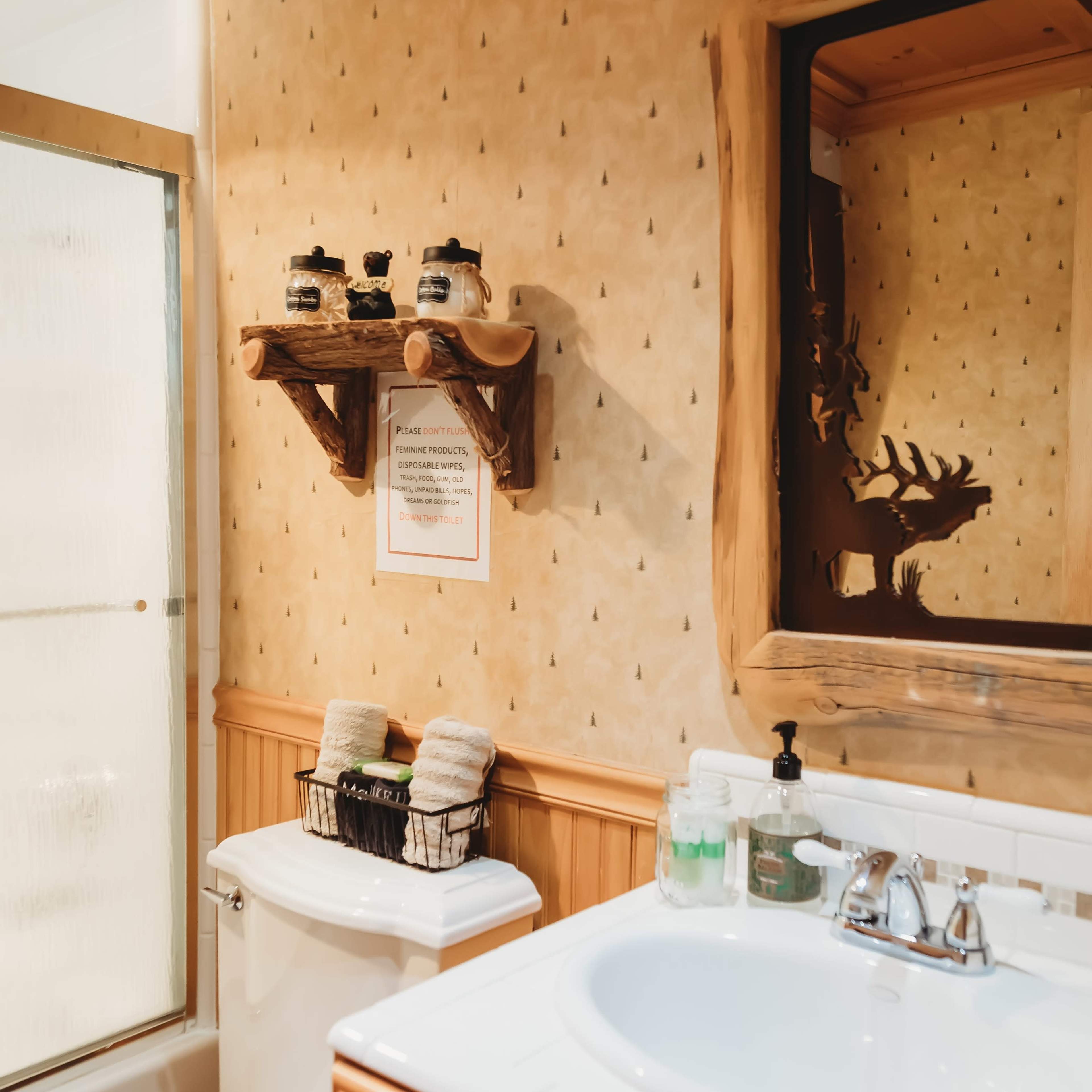 A bathroom featuring a wooden vanity, a mirror, a shower stall, and decorative shelves with various items.