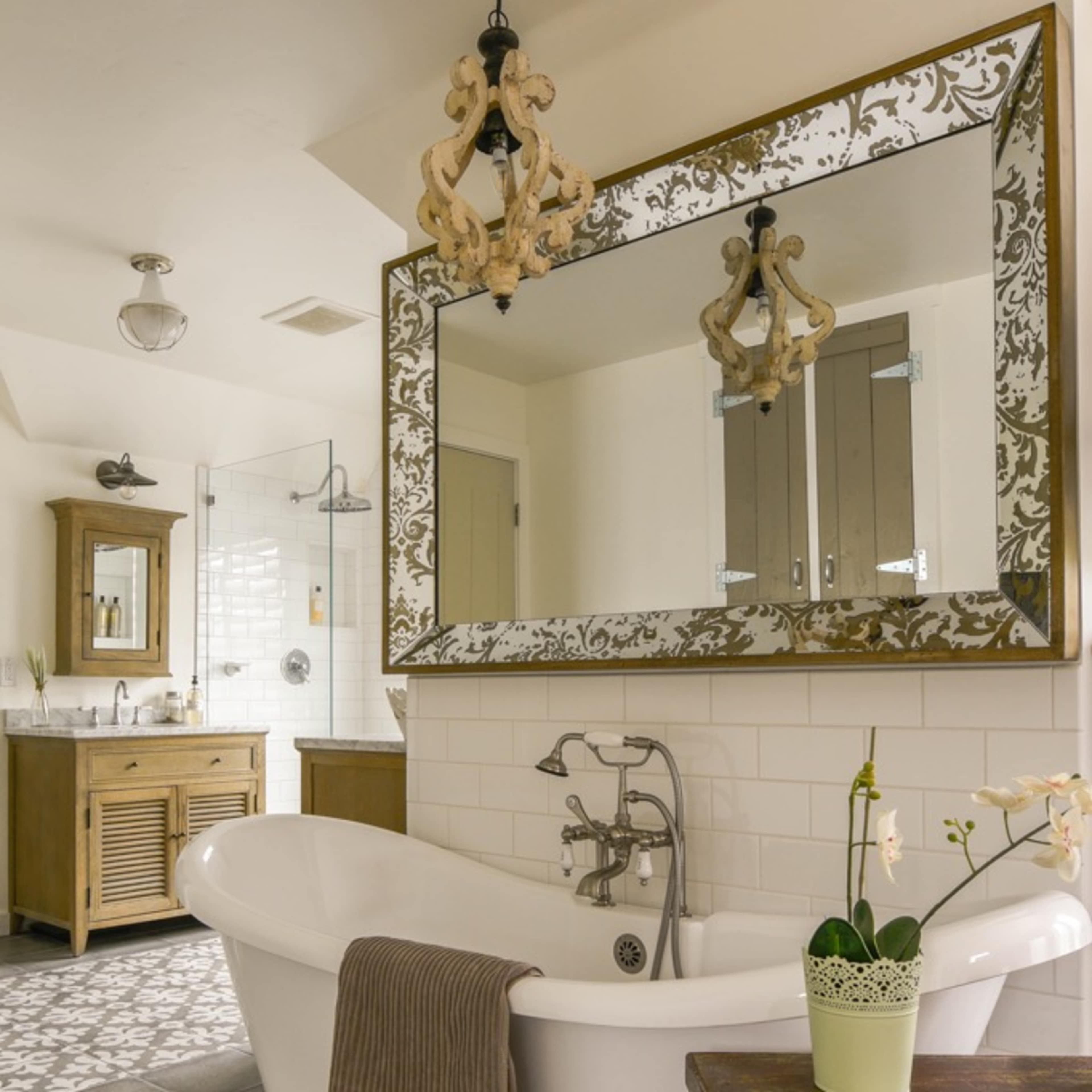A modern bathroom featuring a freestanding bathtub, a large decorative mirror, and wooden furniture with a patterned rug.