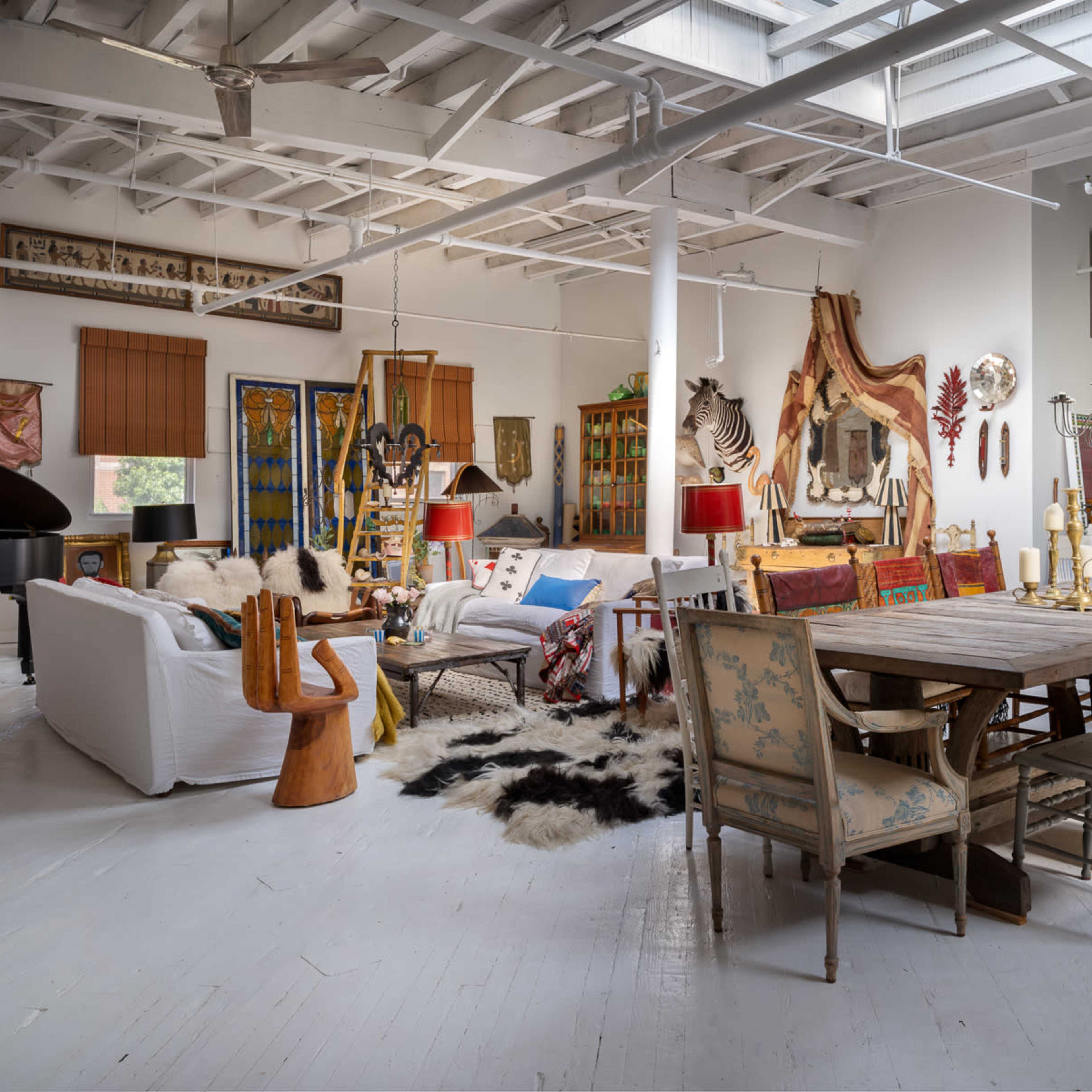 A spacious and eclectic interior with a mix of furniture styles, artwork, and decorative elements in a well-lit room.