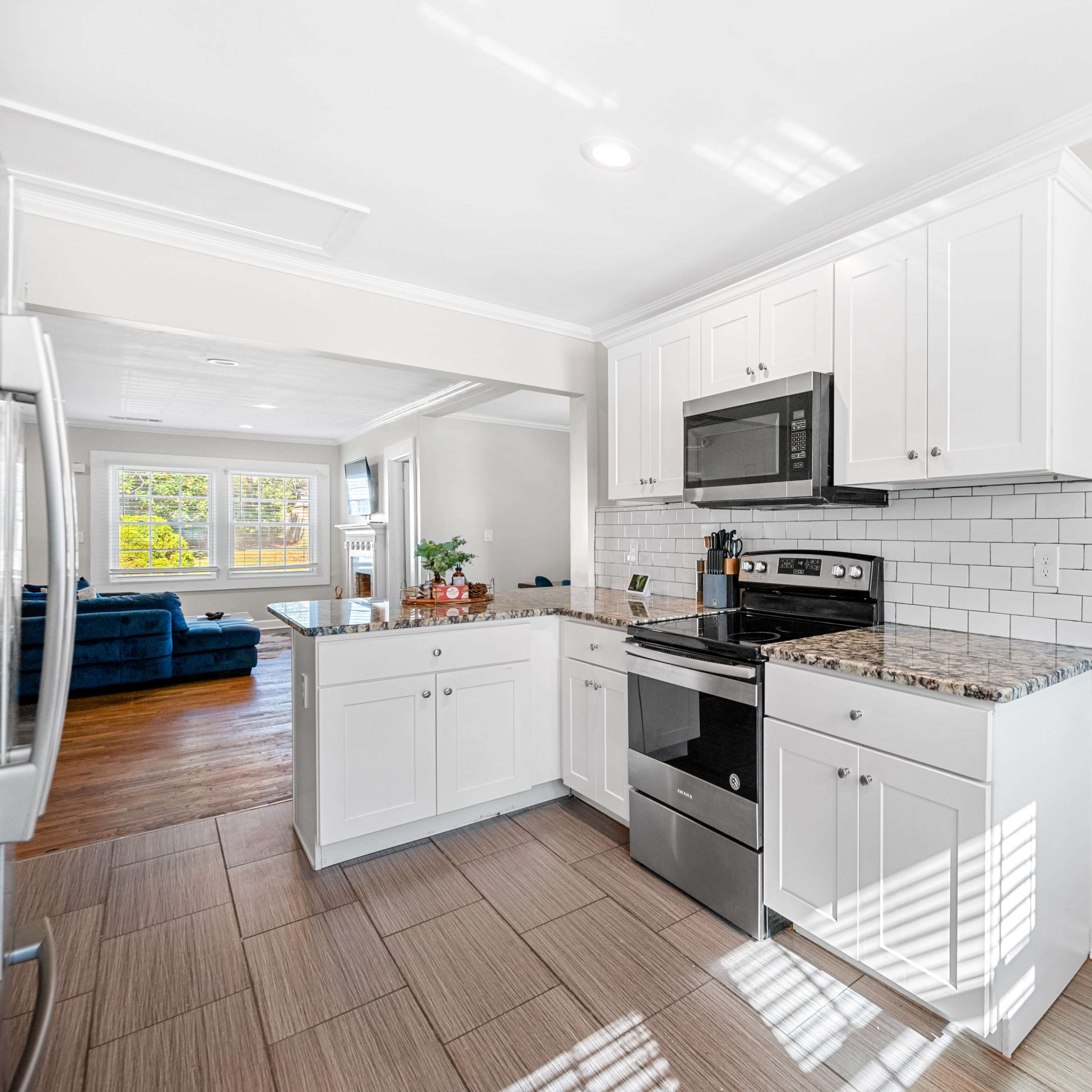 A modern kitchen features white cabinetry, stainless steel appliances, and a tiled backsplash.