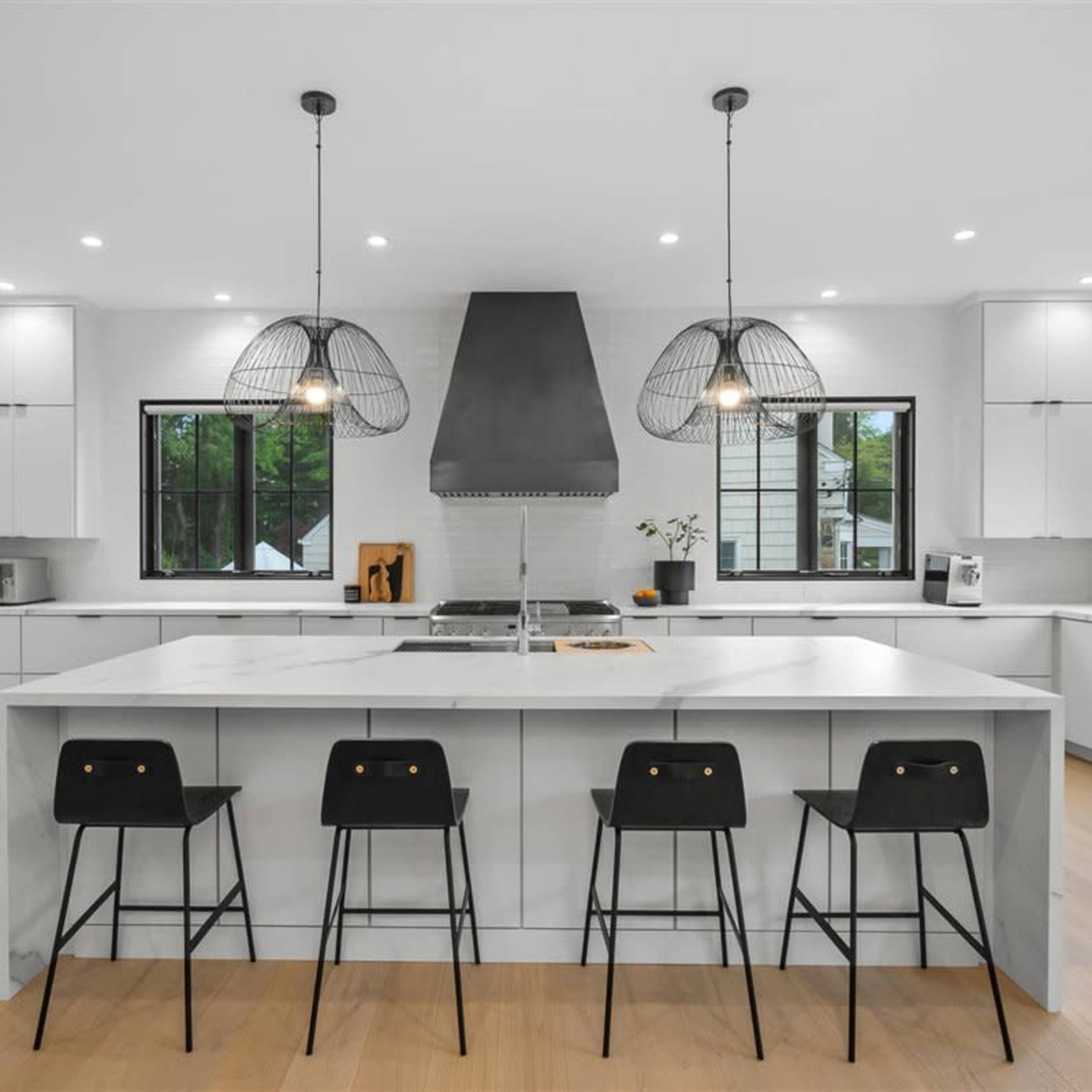 A modern kitchen features a large island with seating, stainless steel appliances, and pendant lighting over the workspace.