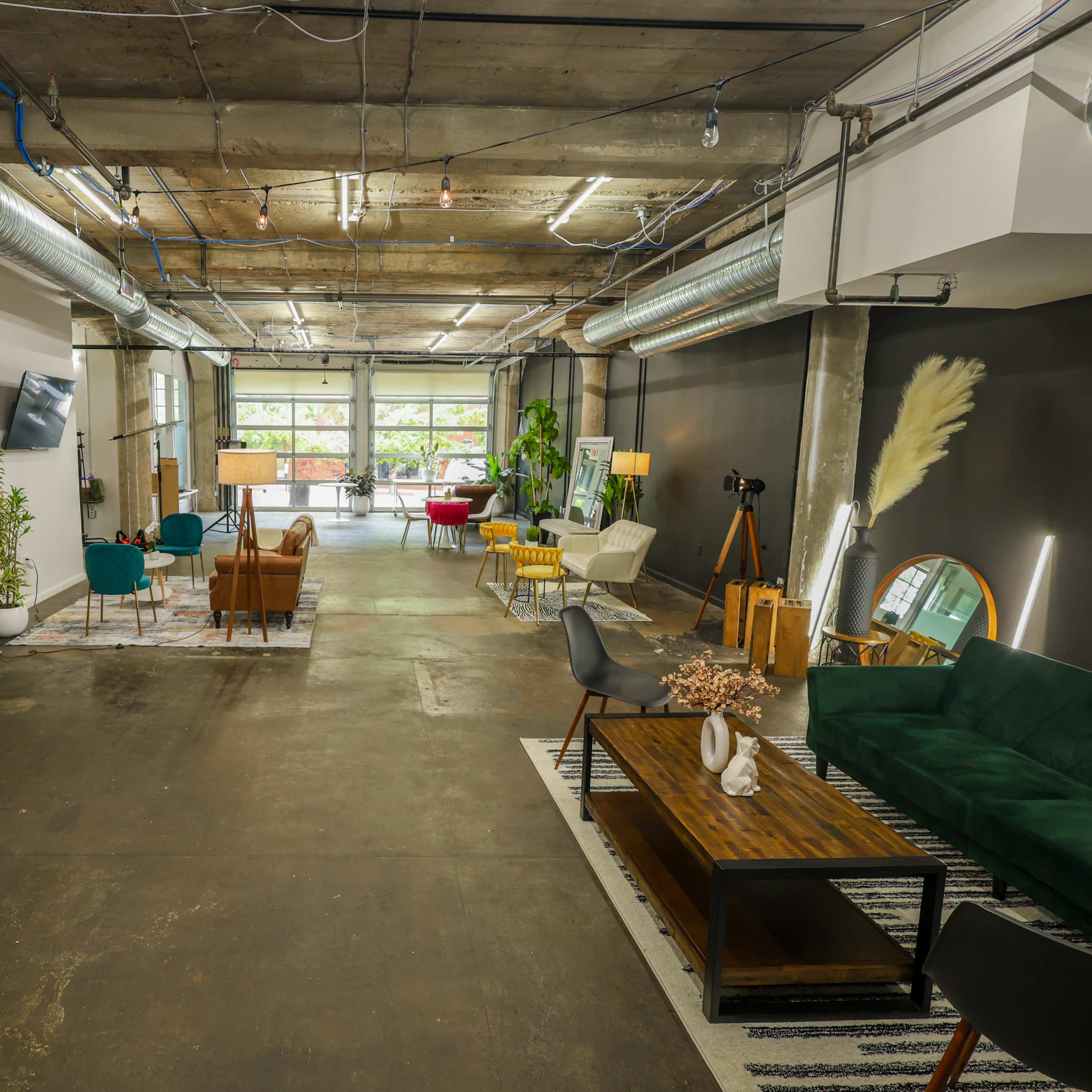 A spacious interior with concrete ceilings, modern furniture, and plants arranged in a well-lit area.