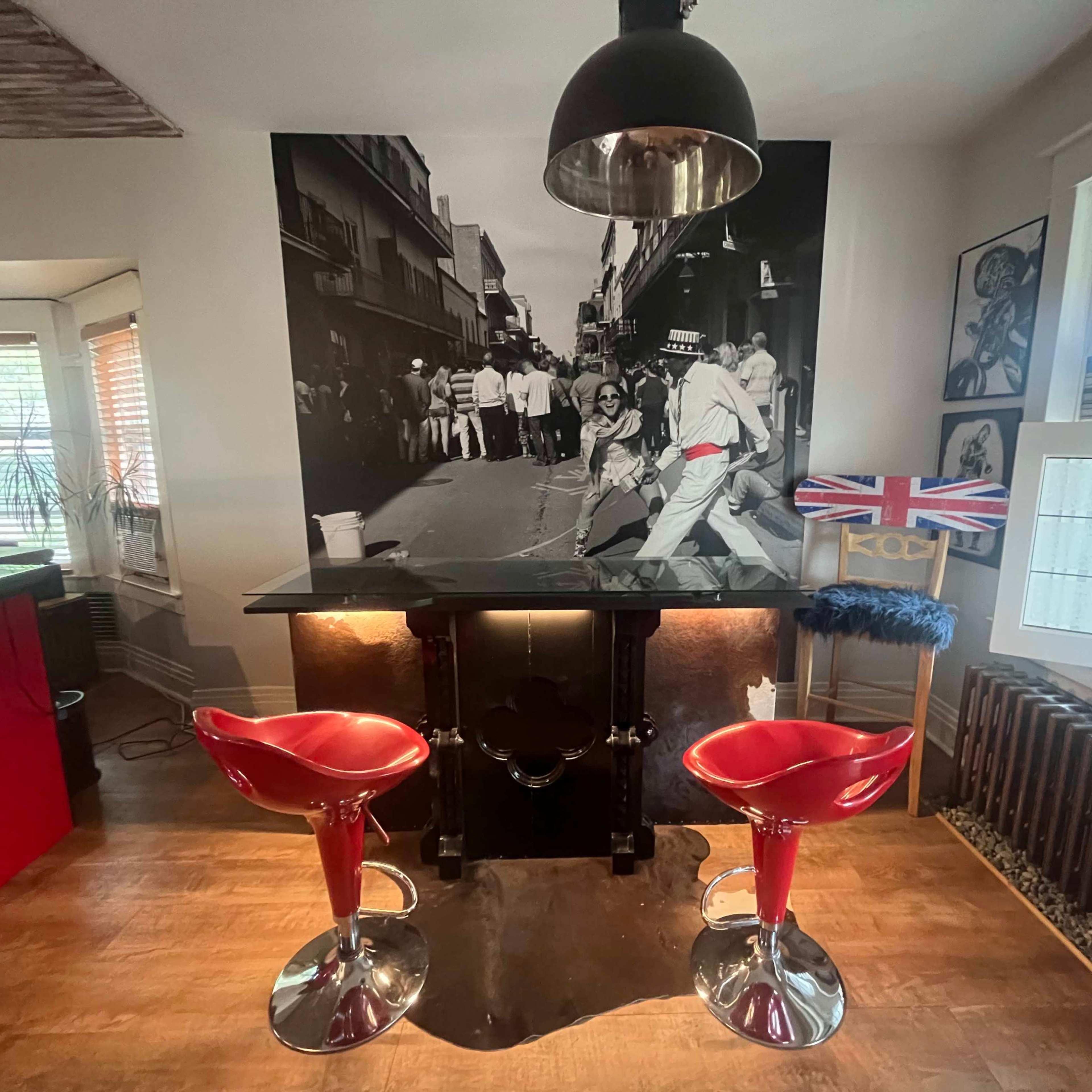 A modern kitchen area featuring two red bar stools in front of a black-and-white mural depicting a street scene.