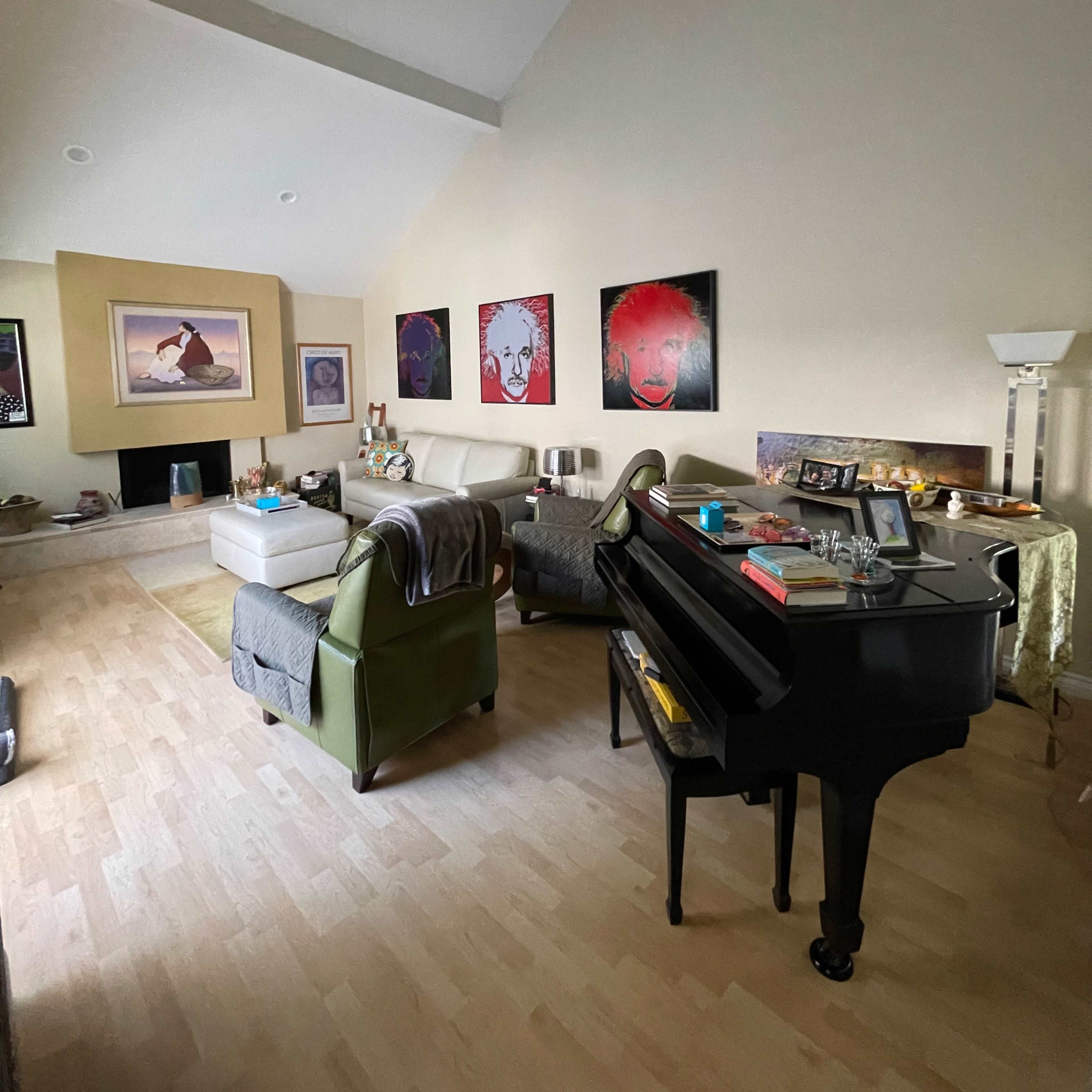 A living room features a grand piano, a seating area with a sofa, and several framed artworks on the walls.