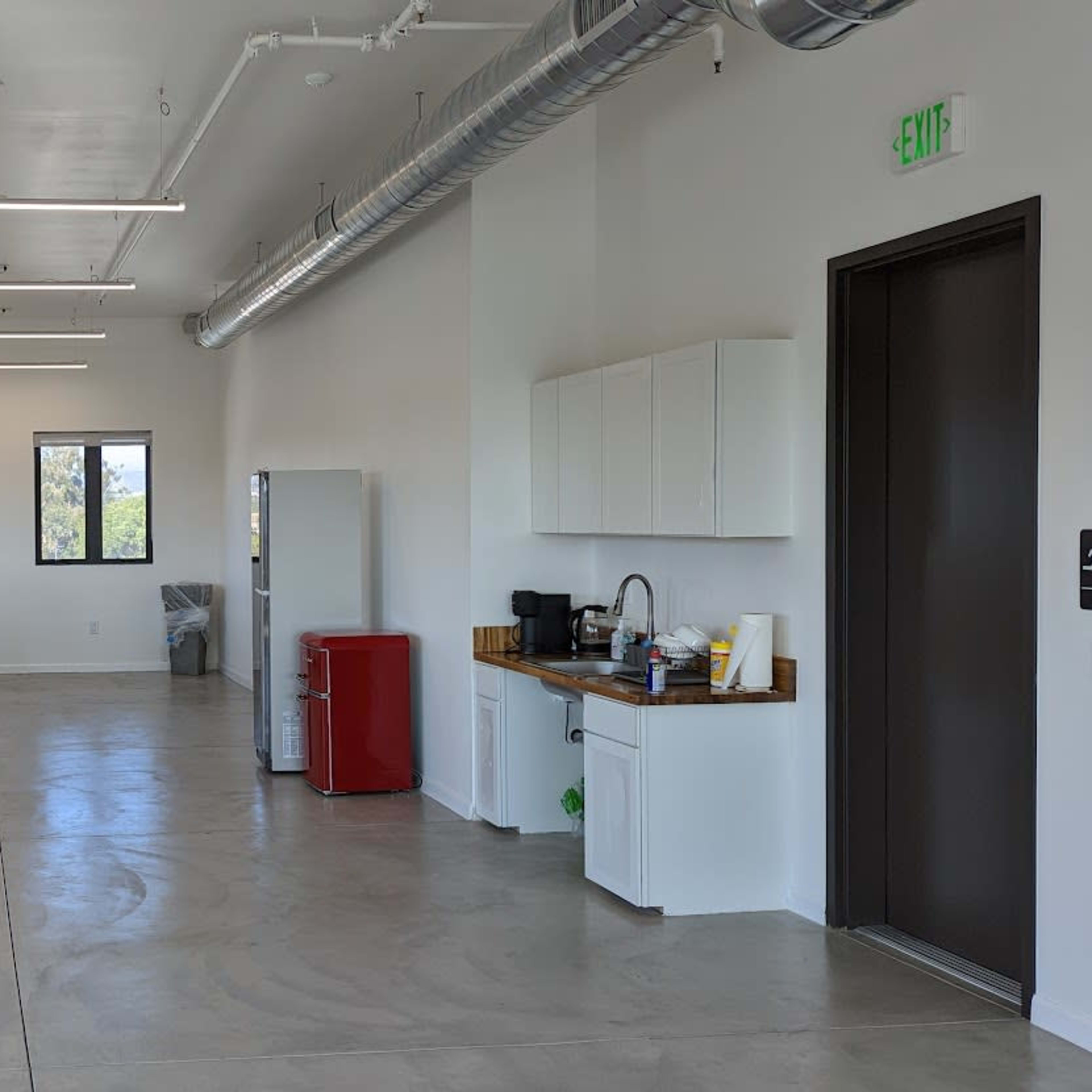 A spacious interior area with modern furnishings, including a kitchen counter, appliances, seating, and several tables.