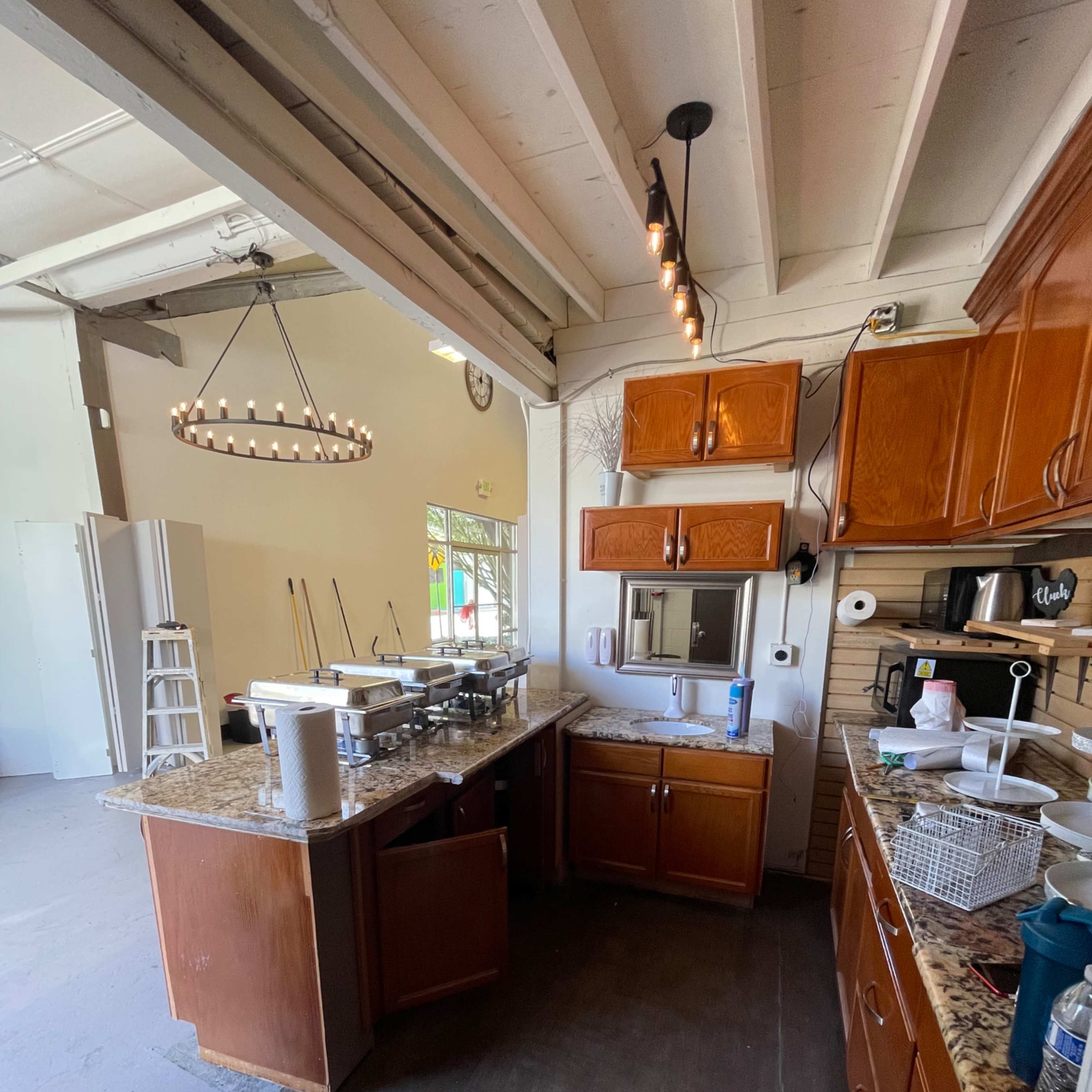 A kitchen with wooden cabinets, a granite countertop, and various appliances is visible, along with a spacious area leading to another room.