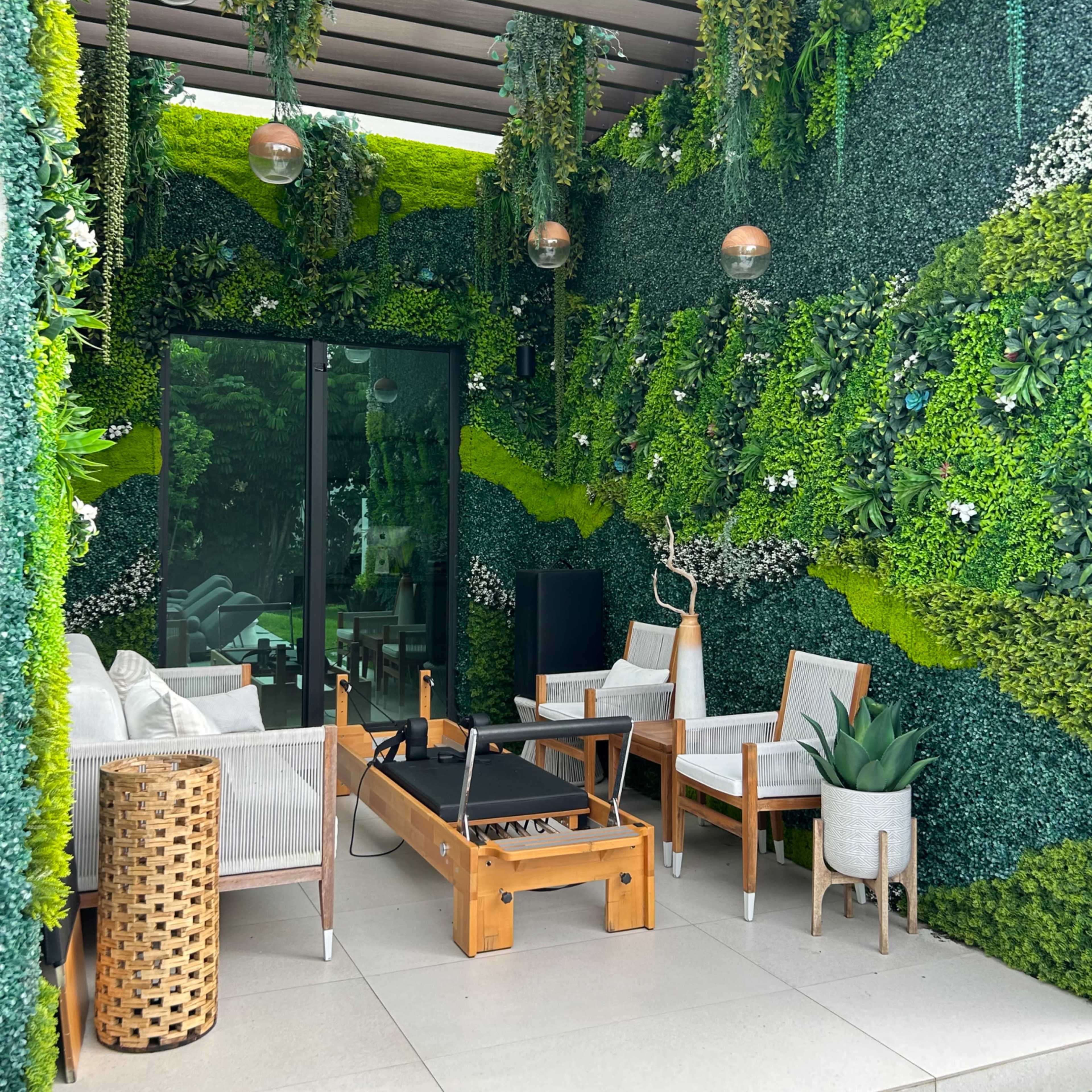 A modern outdoor seating area with green walls covered in plants, featuring a fire pit and comfortable furniture.