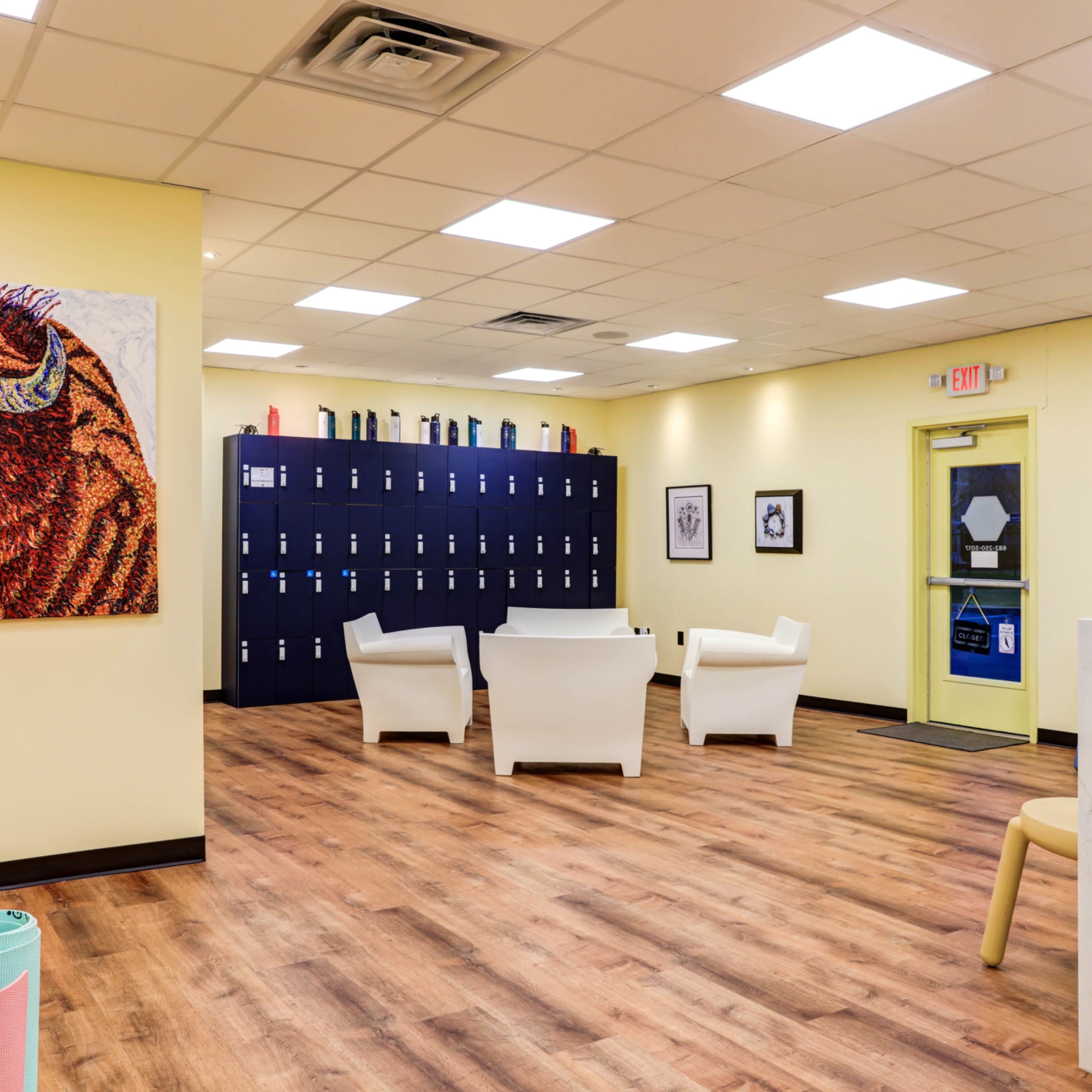 A bright, spacious reception area with lockers against one wall, seating in the center, and a large colorful bison artwork on the opposite wall.