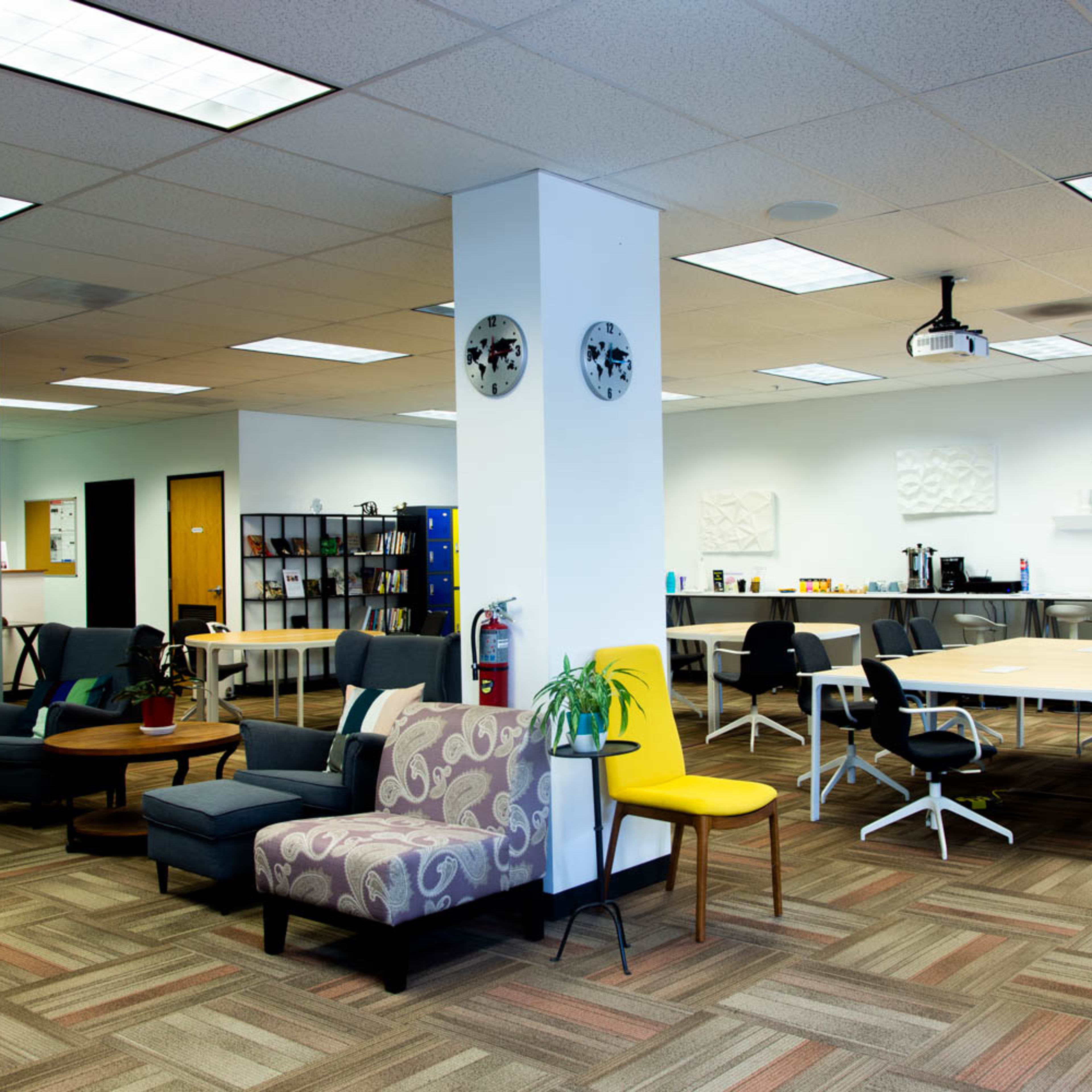 A modern office space featuring a lounge area with comfortable seating and a configuration of tables and chairs in an open layout.