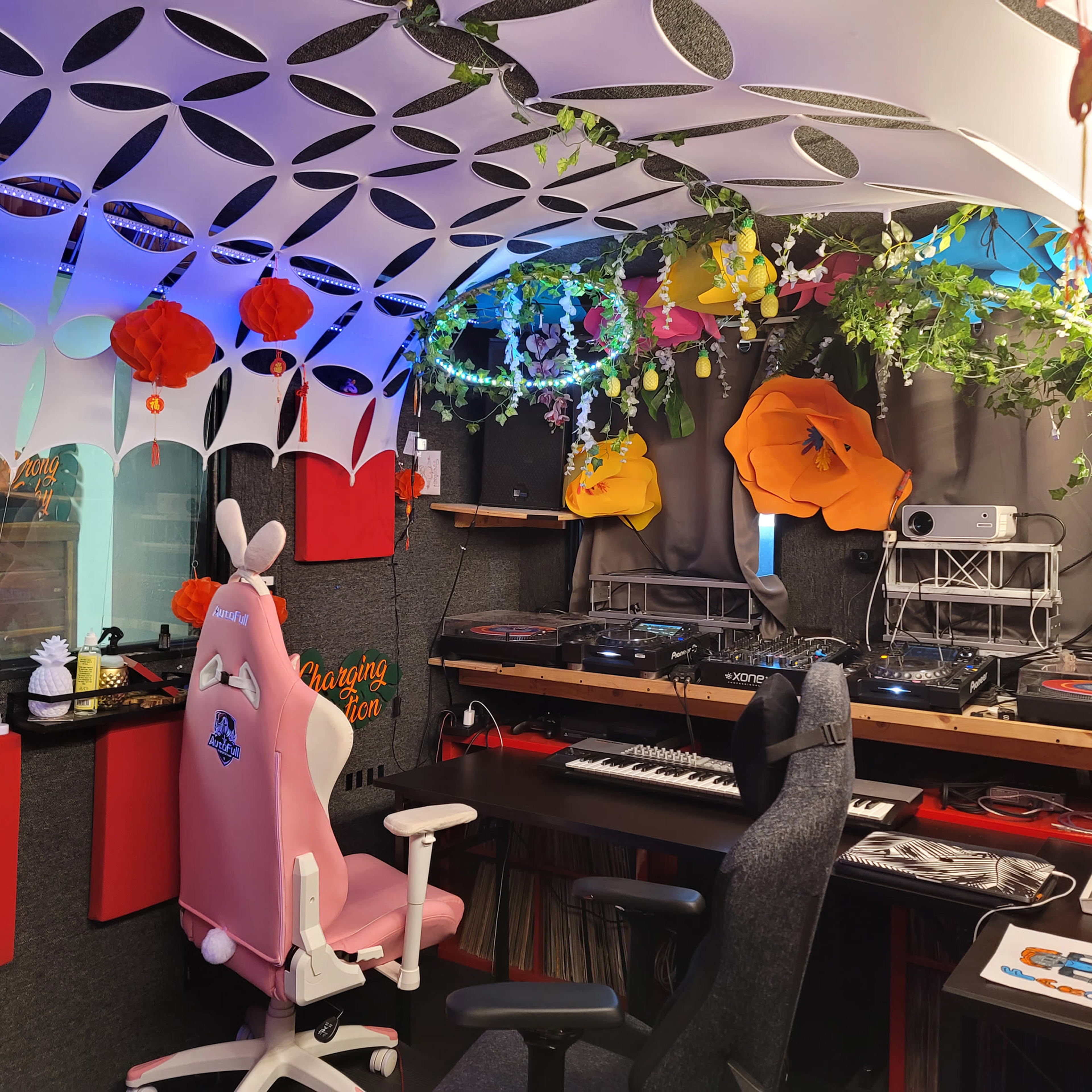 A decorated music studio with DJ equipment, colorful decor, and two ergonomic chairs.