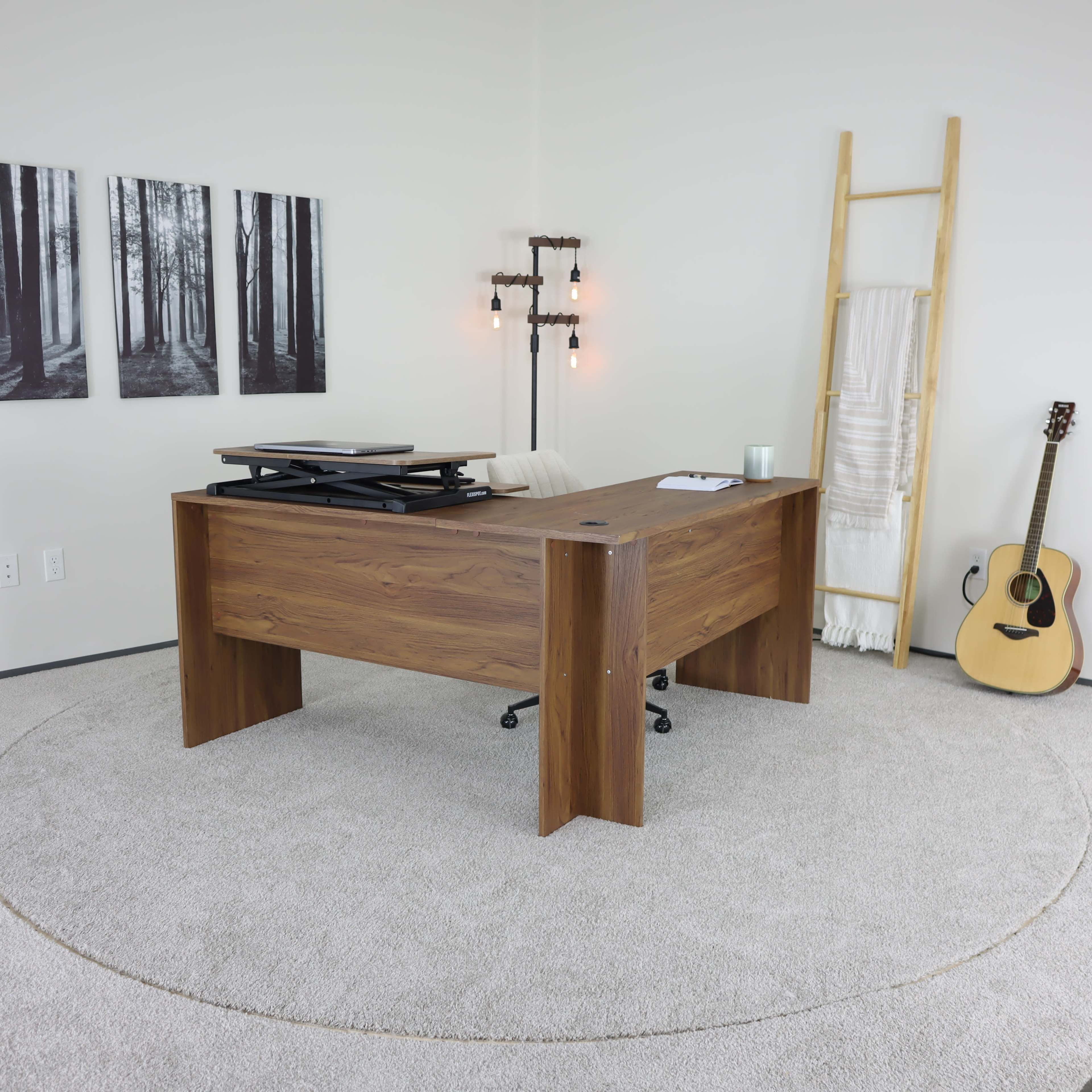 A modern office space features a wooden desk with a rolling chair, surrounded by framed forest photographs and a guitar leaning against a ladder.