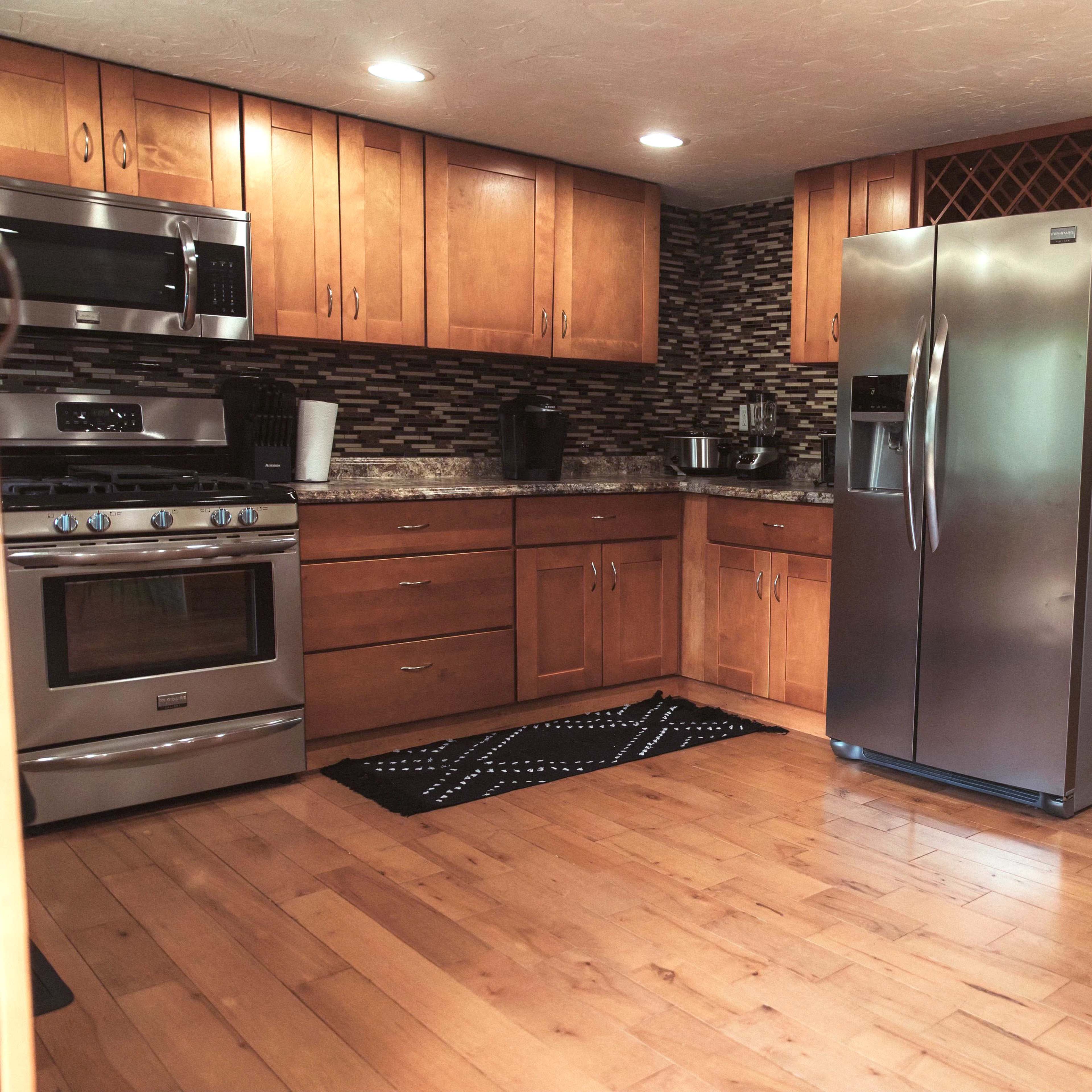 A modern kitchen with wooden cabinets, stainless steel appliances, and a tiled backsplash.