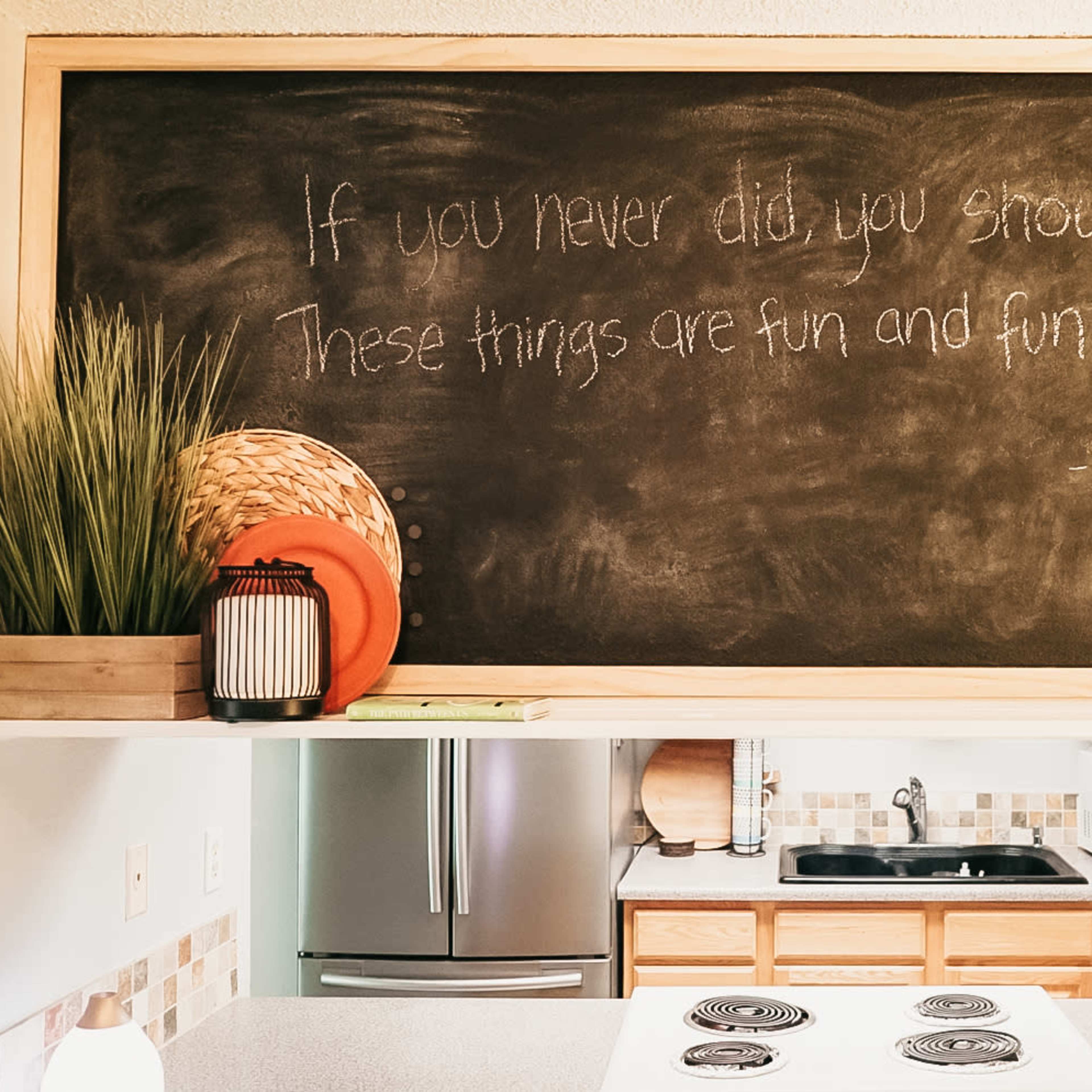 A kitchen with a chalkboard displaying a quote by Dr. Seuss about fun, alongside decorative items such as a plant and a bowl.