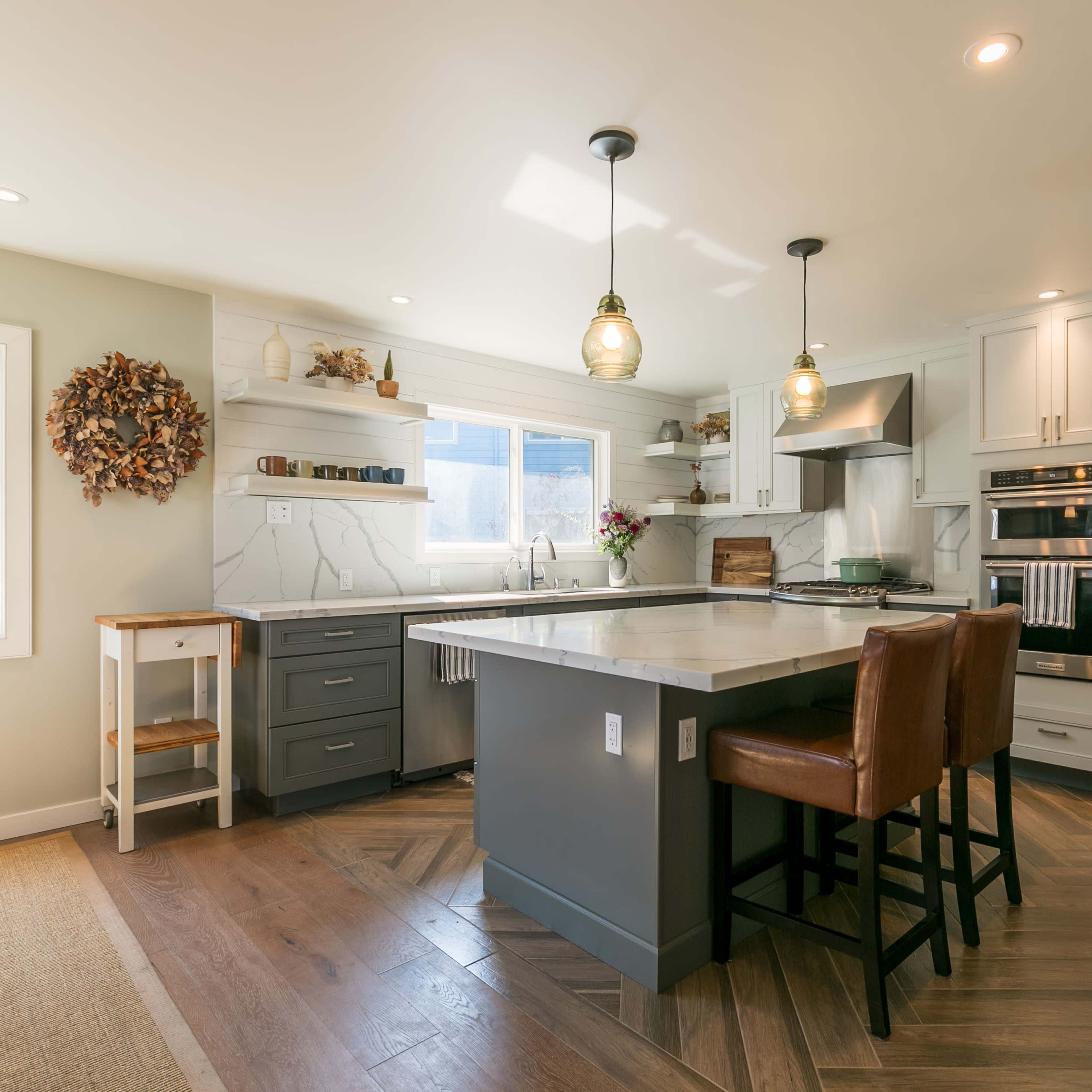 The kitchen features modern cabinetry, stainless steel appliances, a large island with bar seating, and natural light from a window.