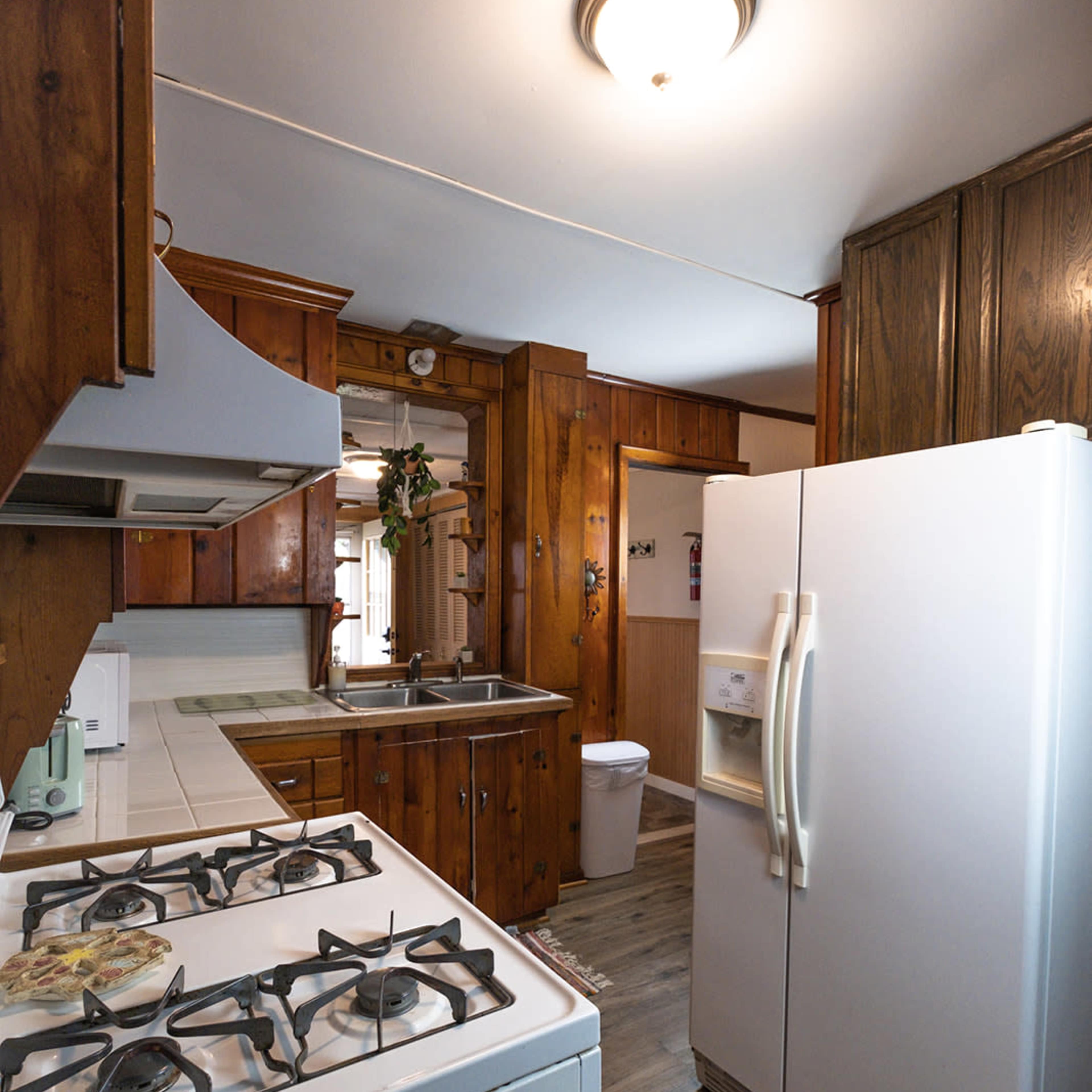 A kitchen with wooden cabinets, a white refrigerator, a gas stove, and a sink, all arranged in a compact space.
