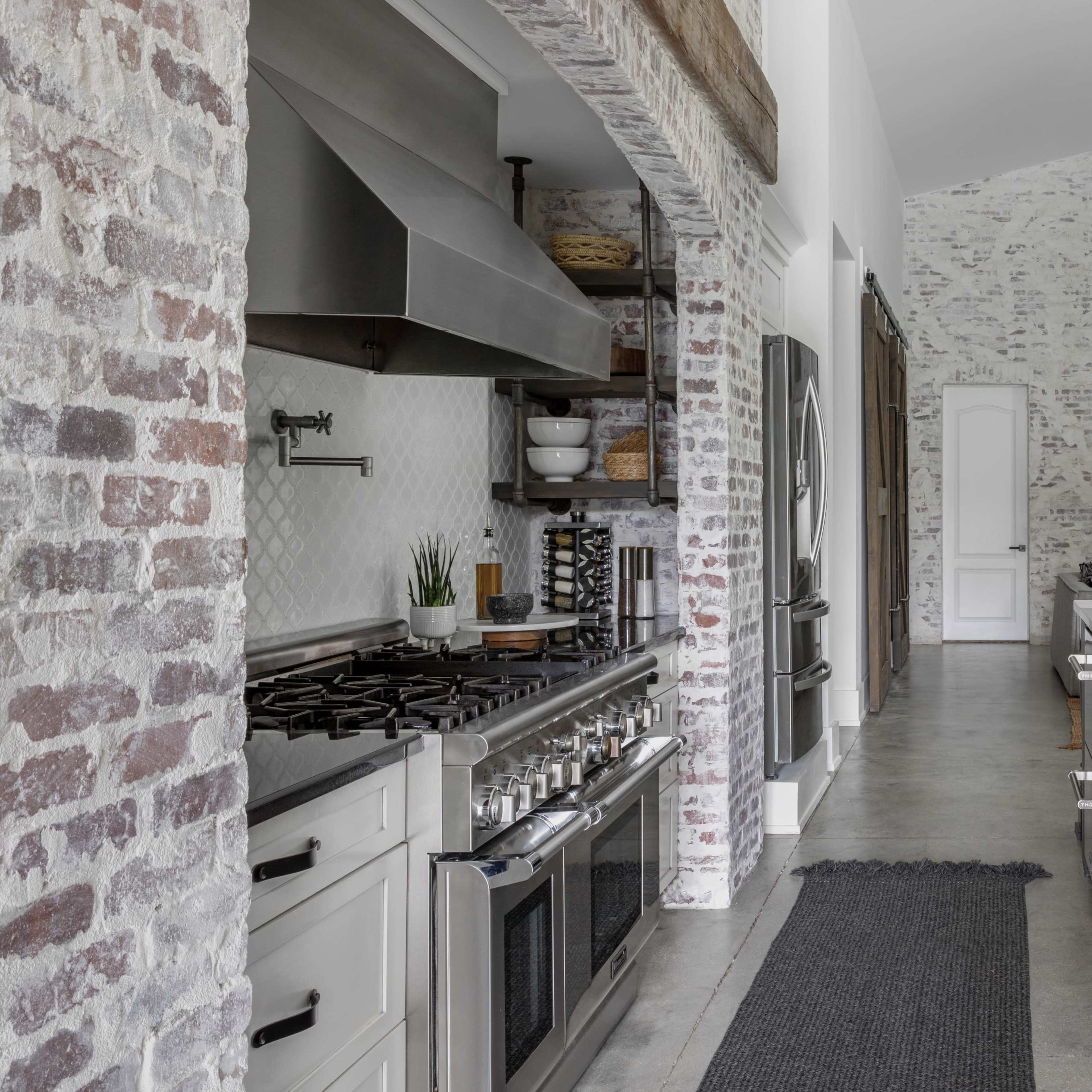 A modern kitchen featuring exposed brick walls, stainless steel appliances, and a central island with a sleek countertop.