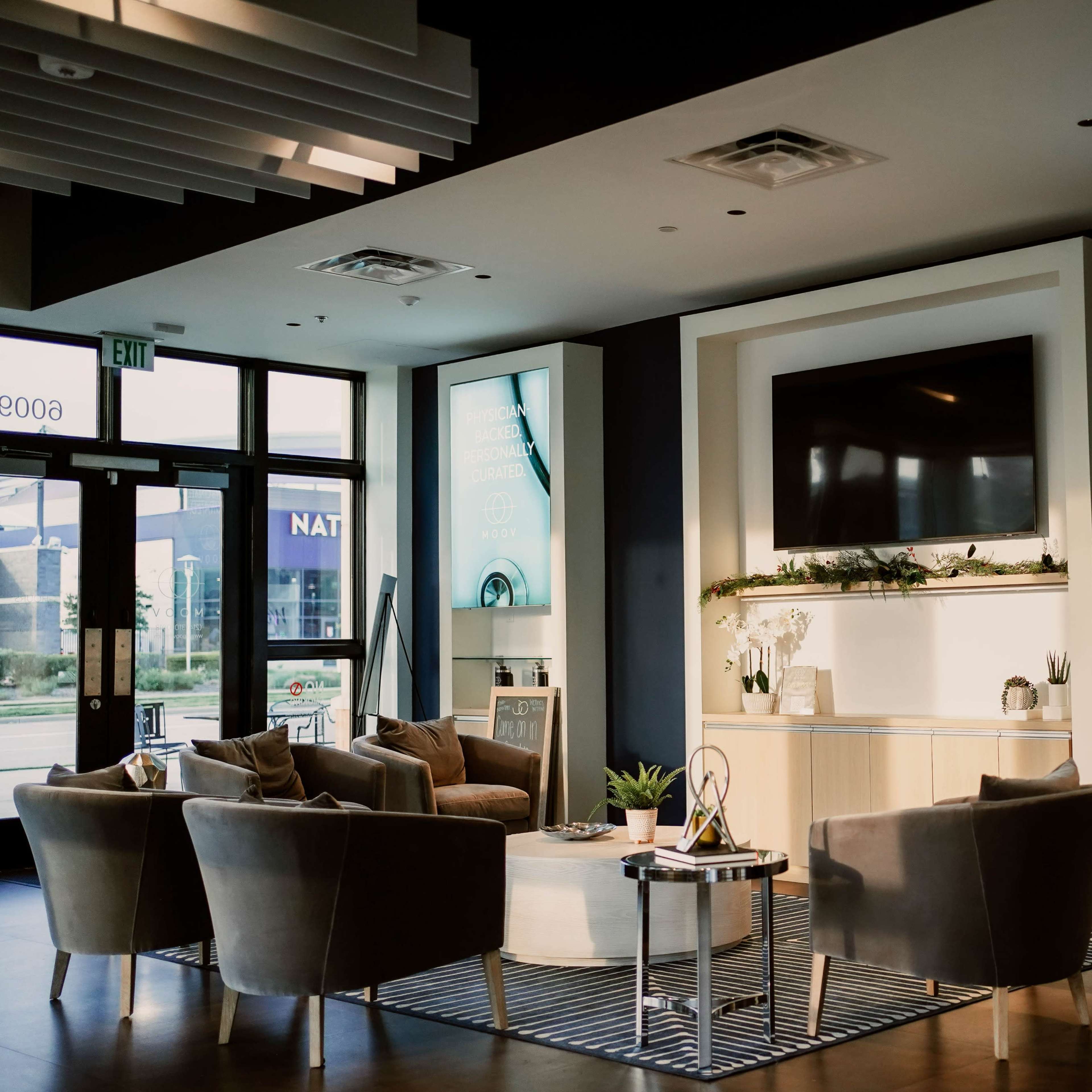 A modern waiting area features stylish seating arrangements, large digital displays, and contemporary decor.