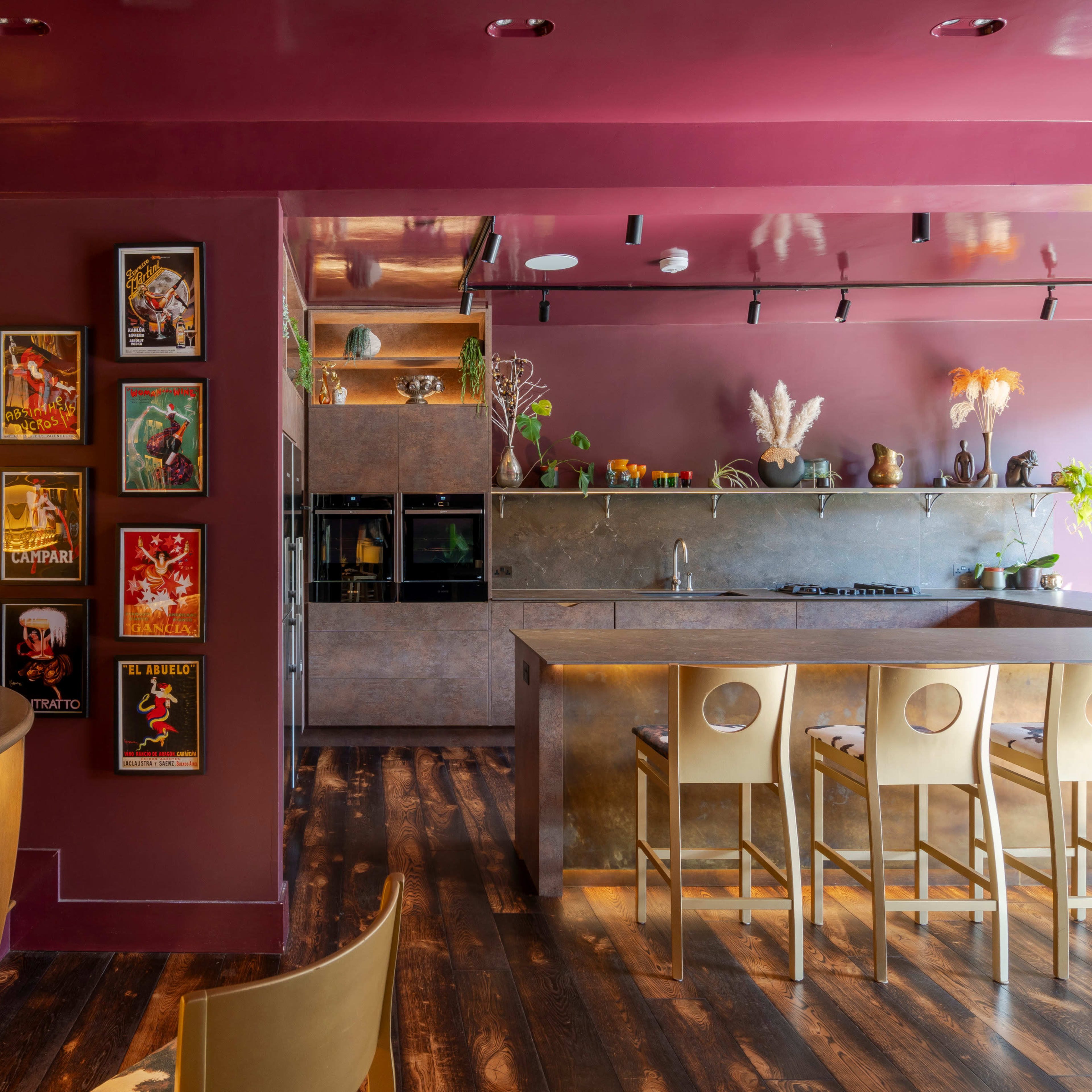 A stylish interior of a restaurant or café featuring a maroon color scheme, modern kitchen appliances, and framed artwork on the walls.