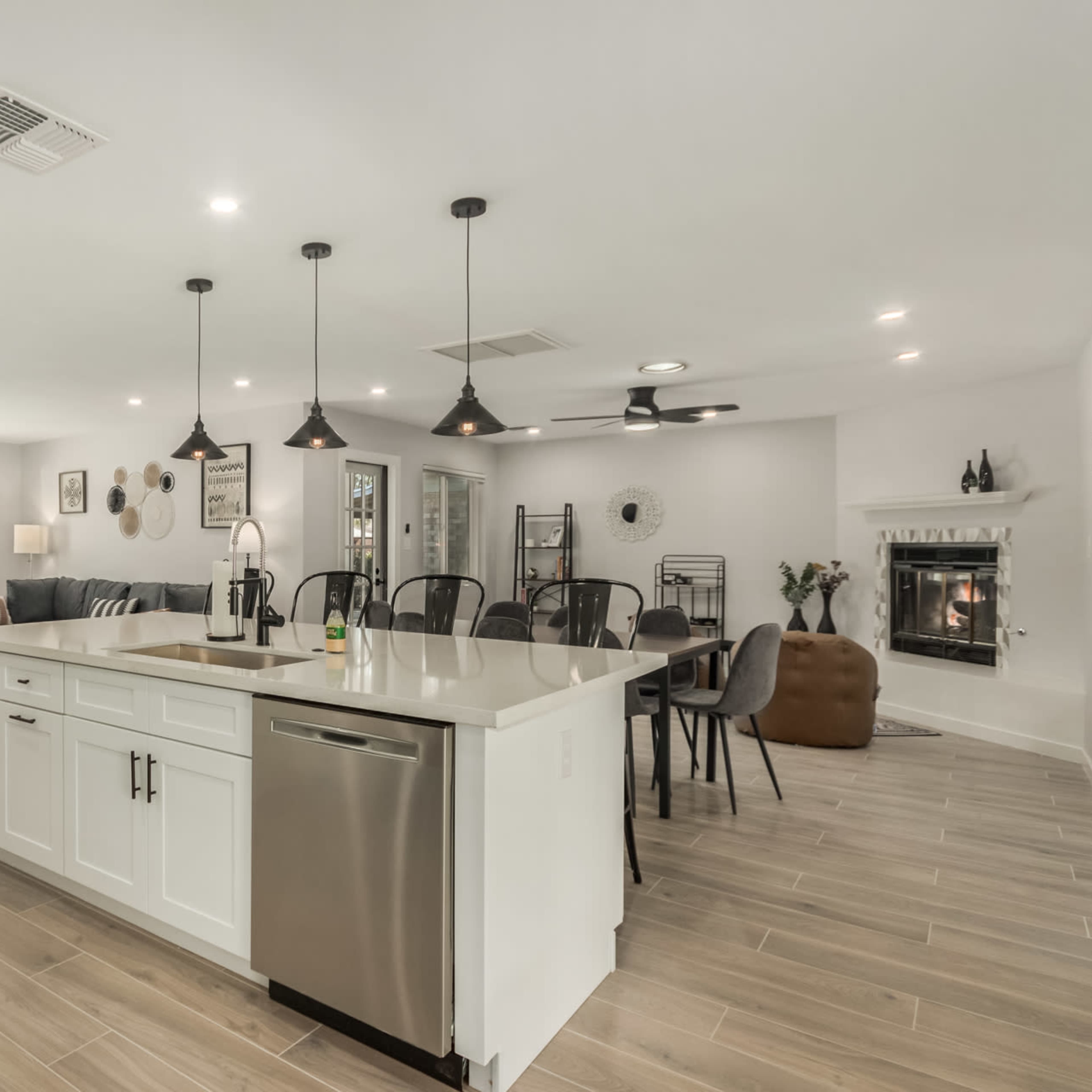 A modern kitchen and living area with an island, stainless steel appliances, and a large window overlooking the front yard.