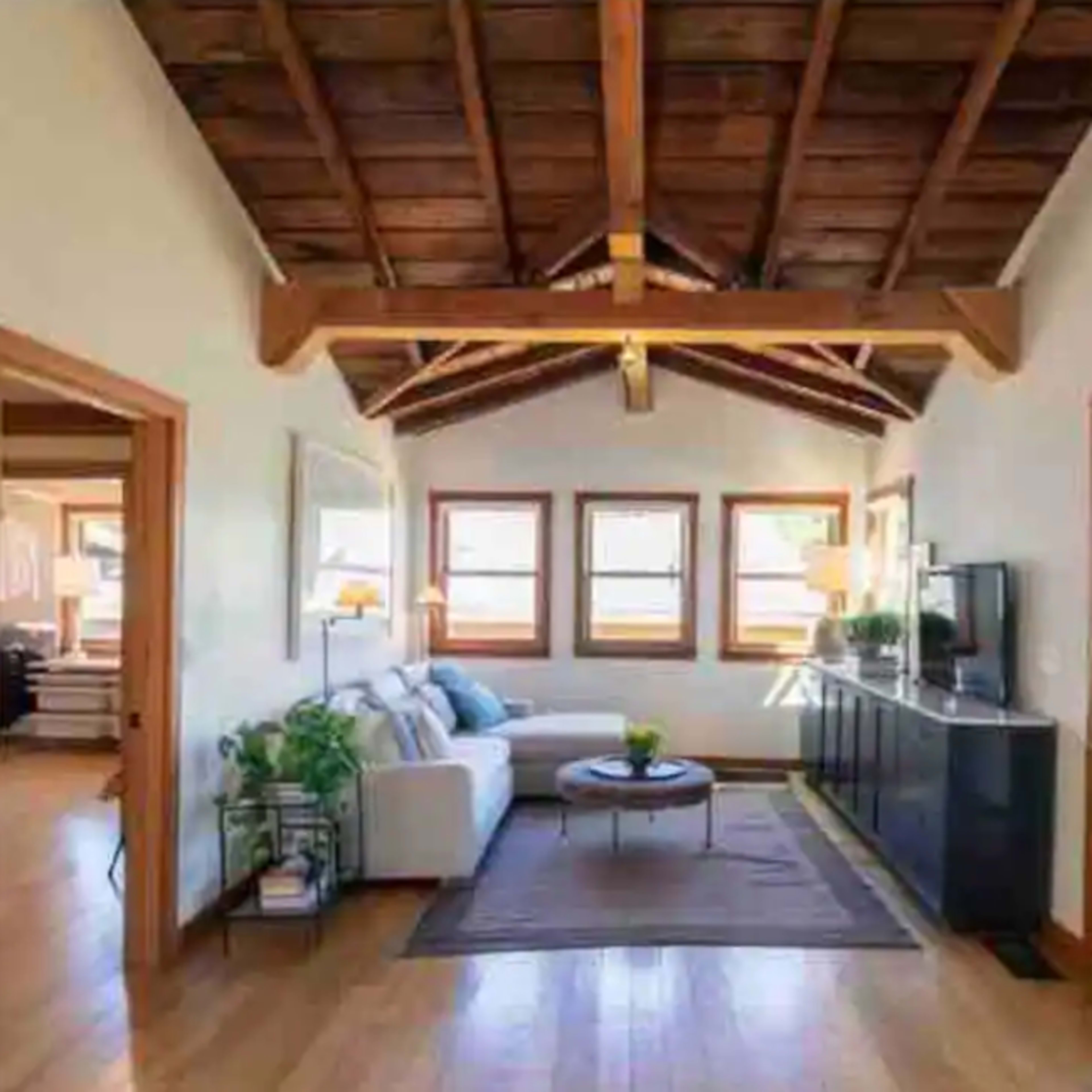 A living room featuring a white sectional sofa, a coffee table with a small plant, and large windows that allow natural light to enter.