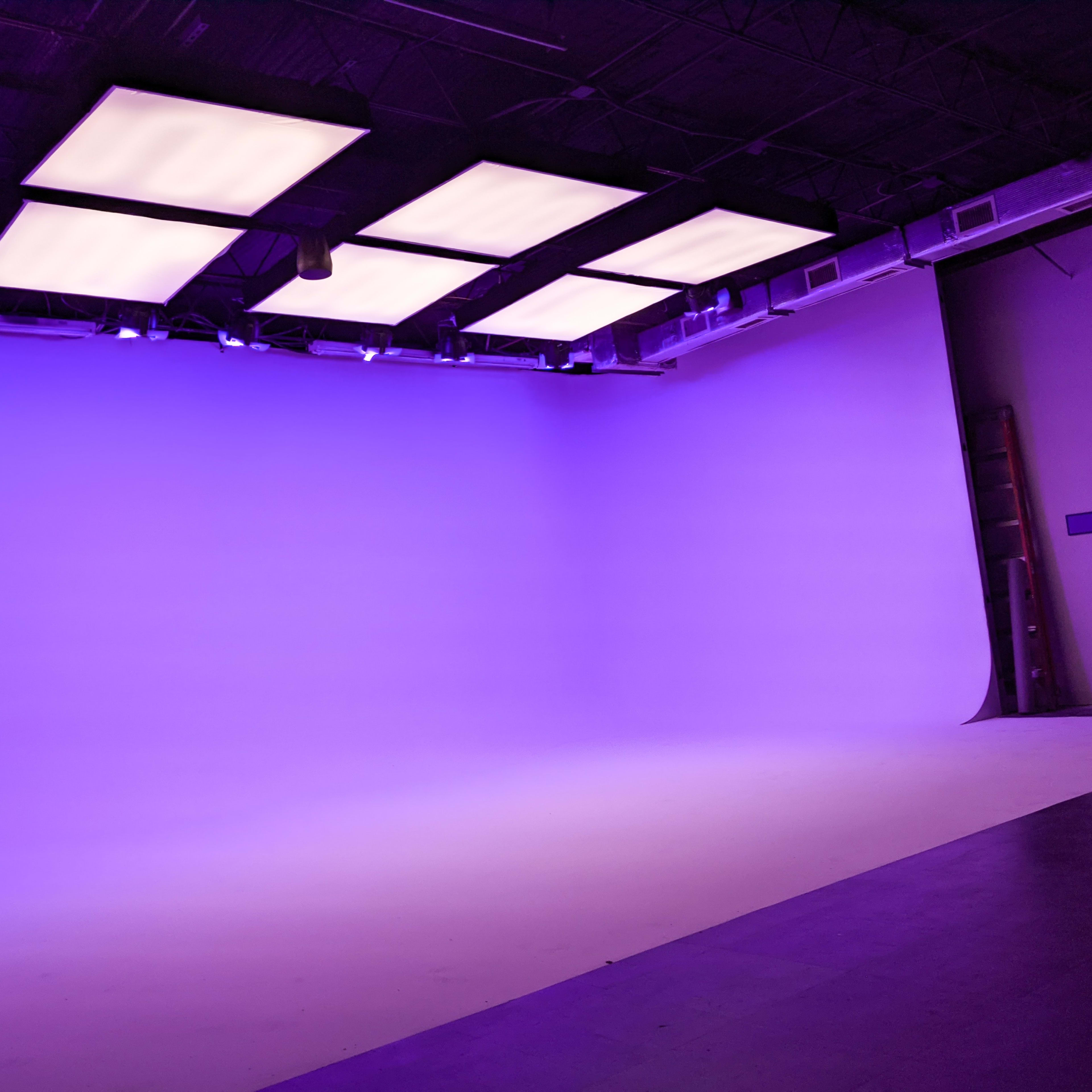 A photography studio featuring a smooth purple backdrop and bright ceiling lights.