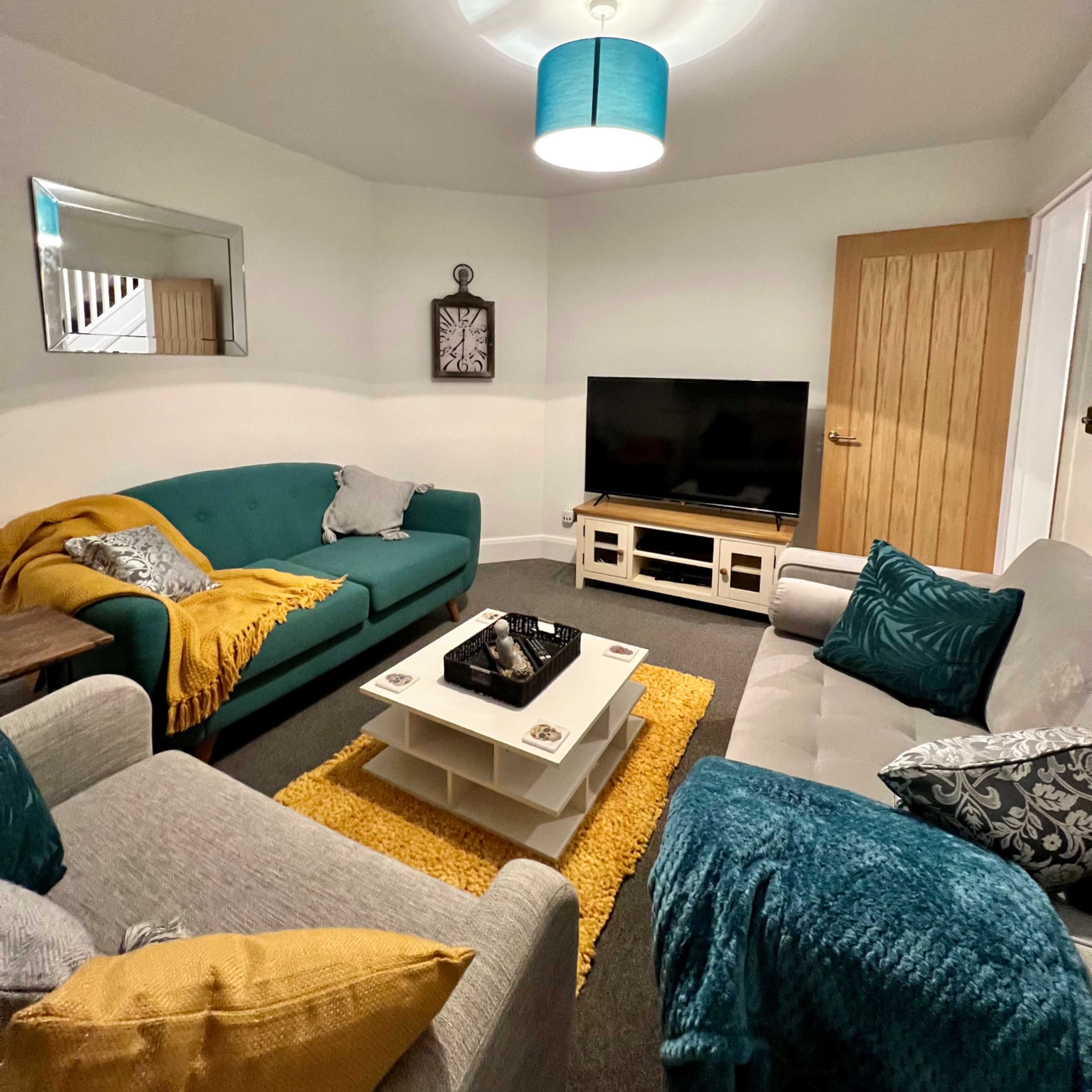 A cozy living room features two sofas, a coffee table, a television, and decorative items against neutral walls.