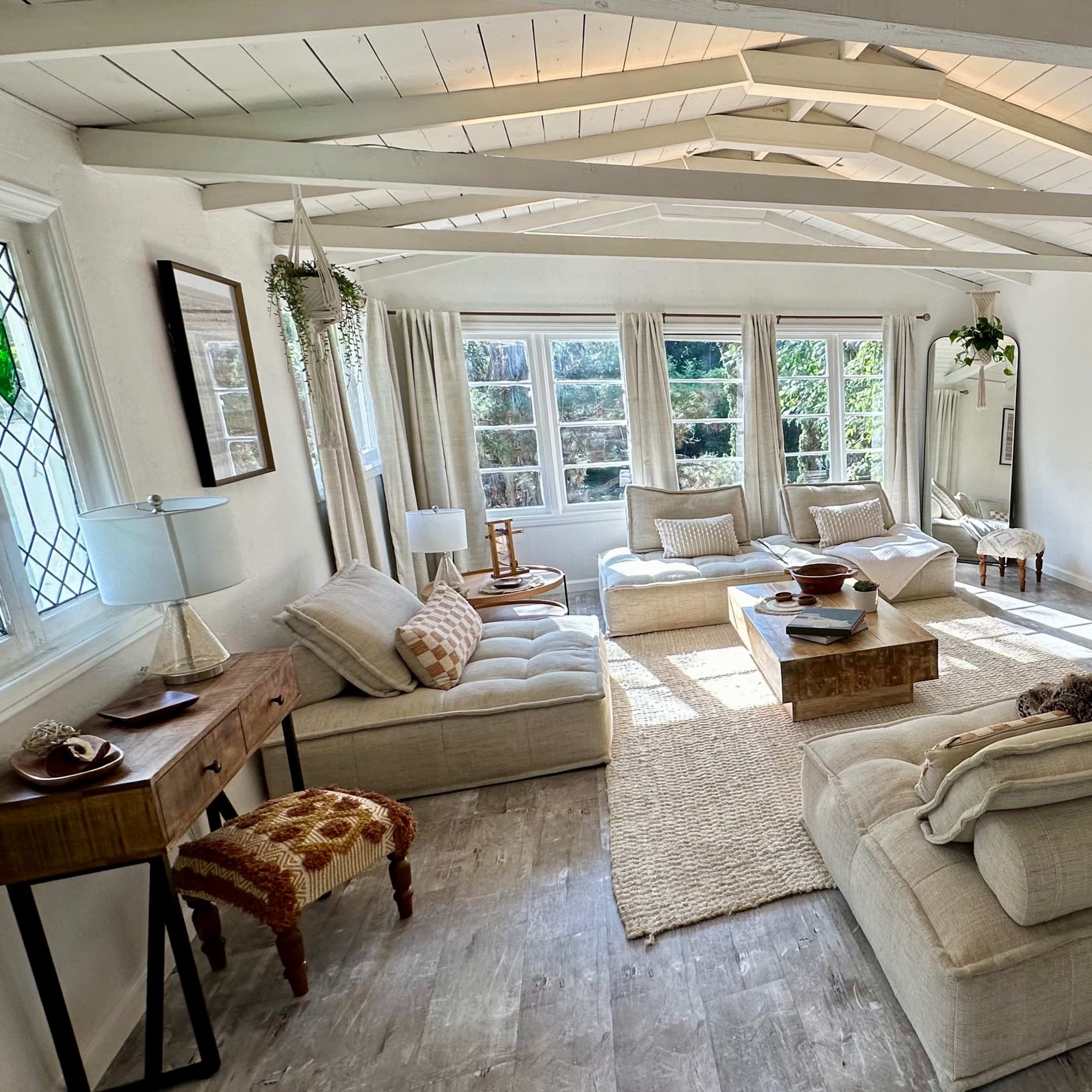 The living room features a cozy arrangement of sofas and a stone fireplace, with large windows allowing natural light to fill the space.