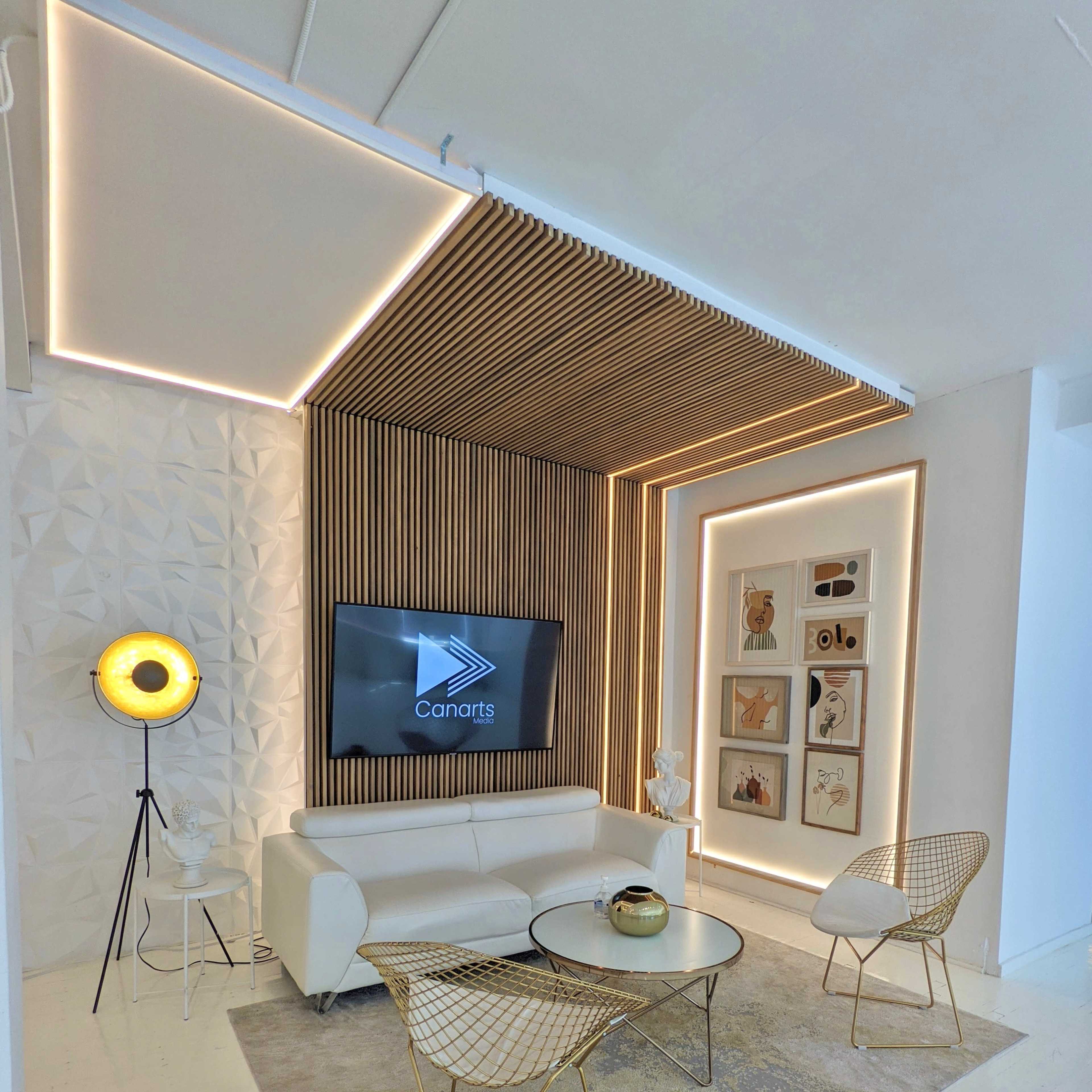 A modern seating area with a white sofa, gold-accented chairs, a round glass coffee table, and wall art, illuminated by ambient lighting.
