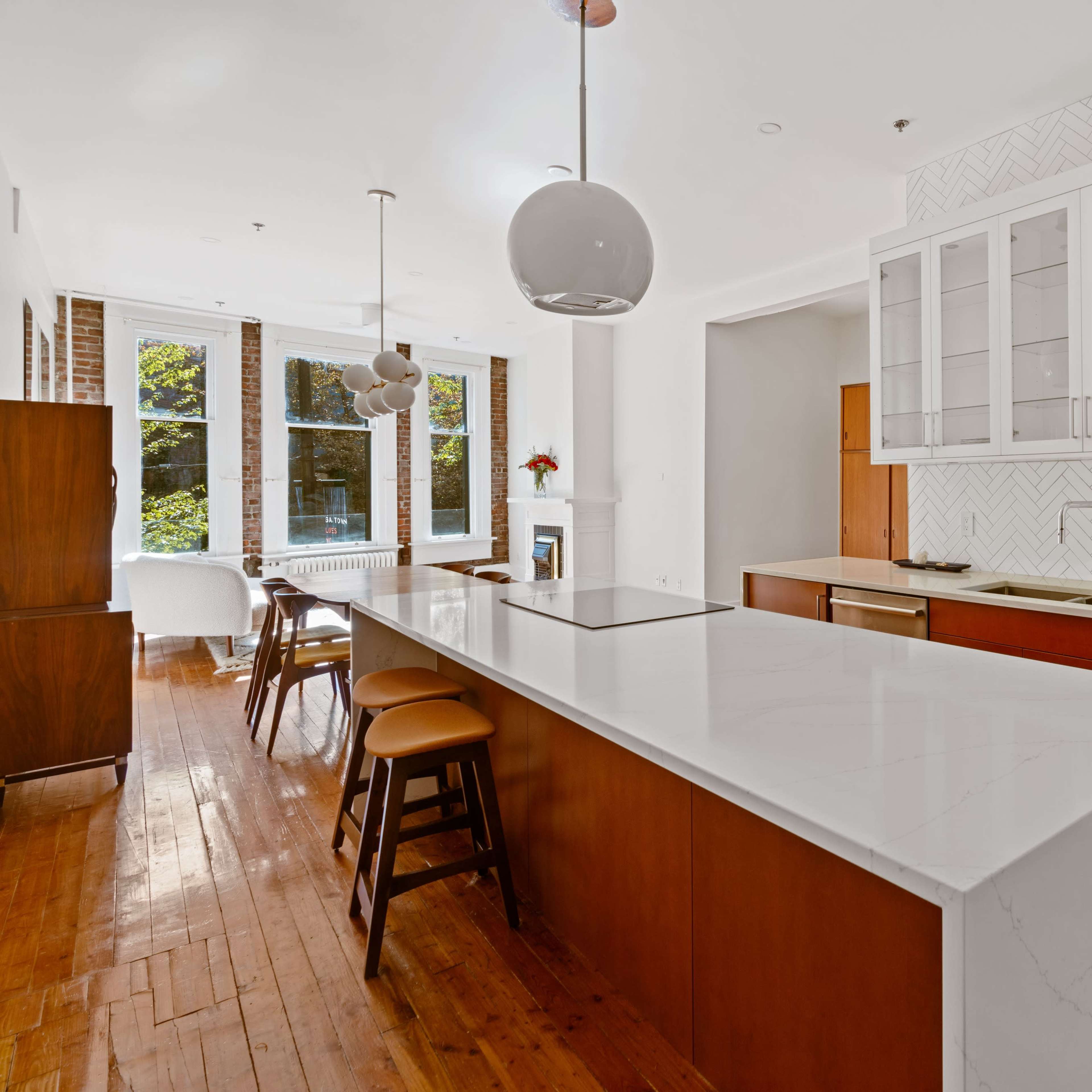 A modern kitchen with a central island, stainless steel appliances, and large windows allowing natural light to fill the space.