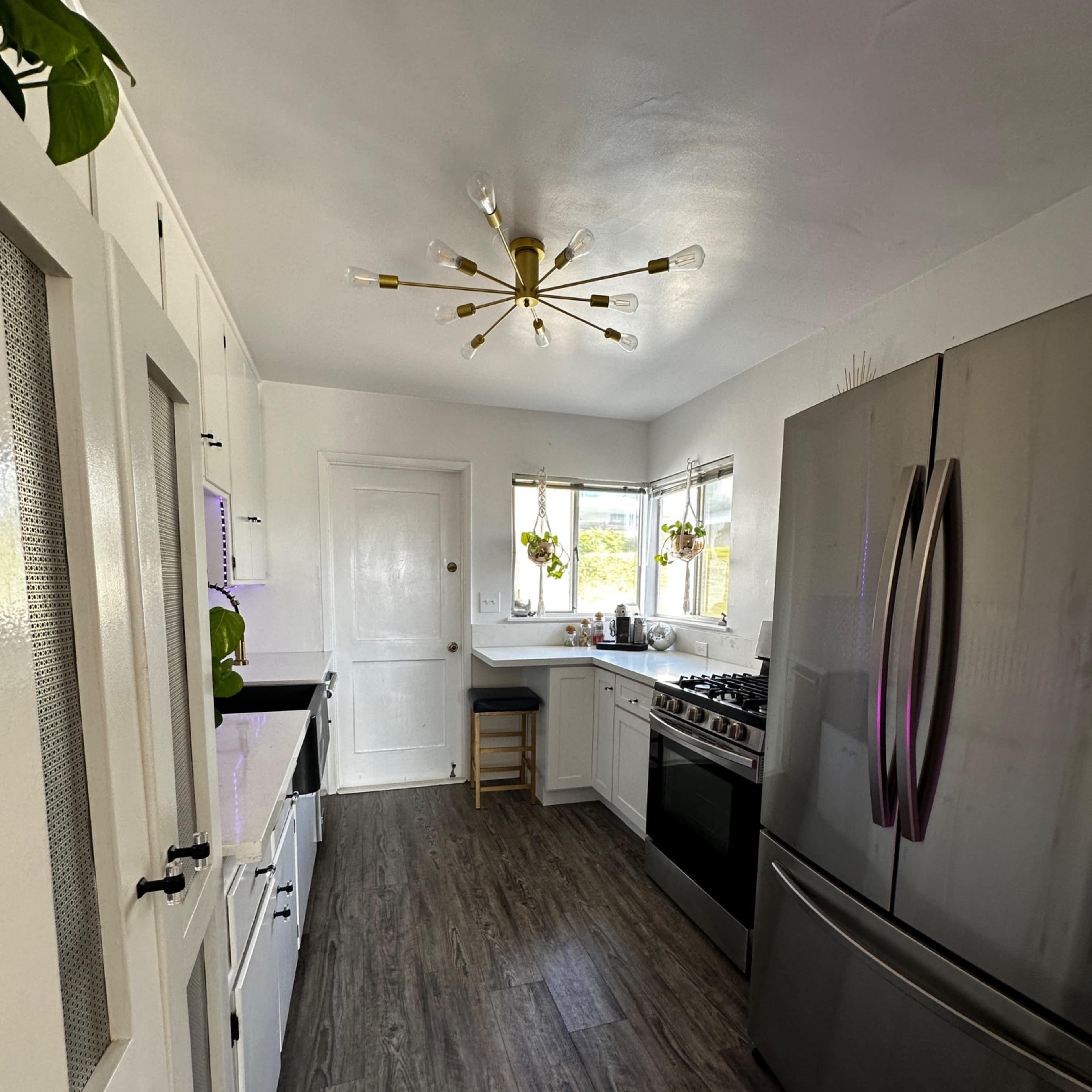 A modern kitchen equipped with stainless steel appliances, white cabinetry, and a central island with a stool.
