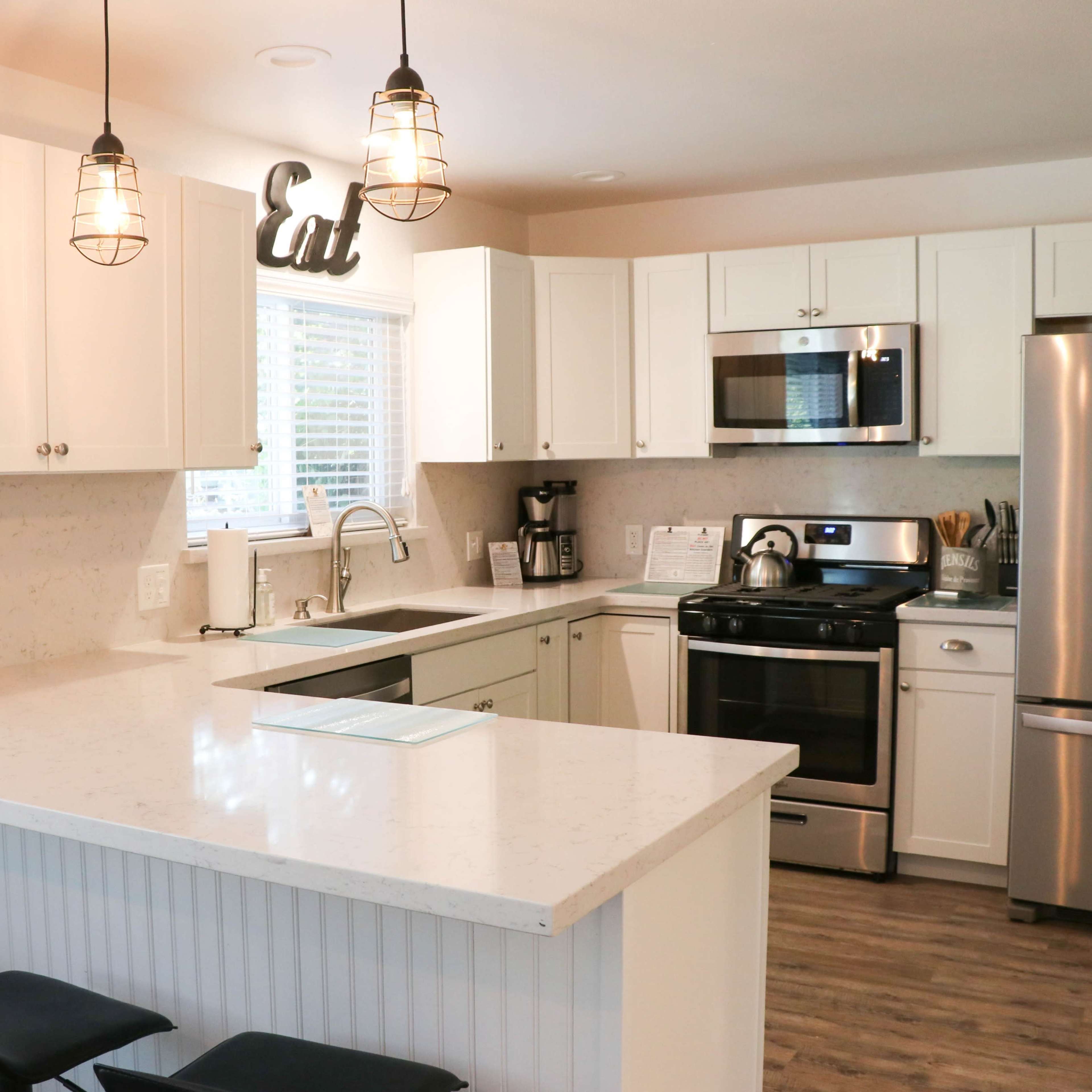 A modern kitchen features white cabinetry, stainless steel appliances, and a spacious island with bar stools.