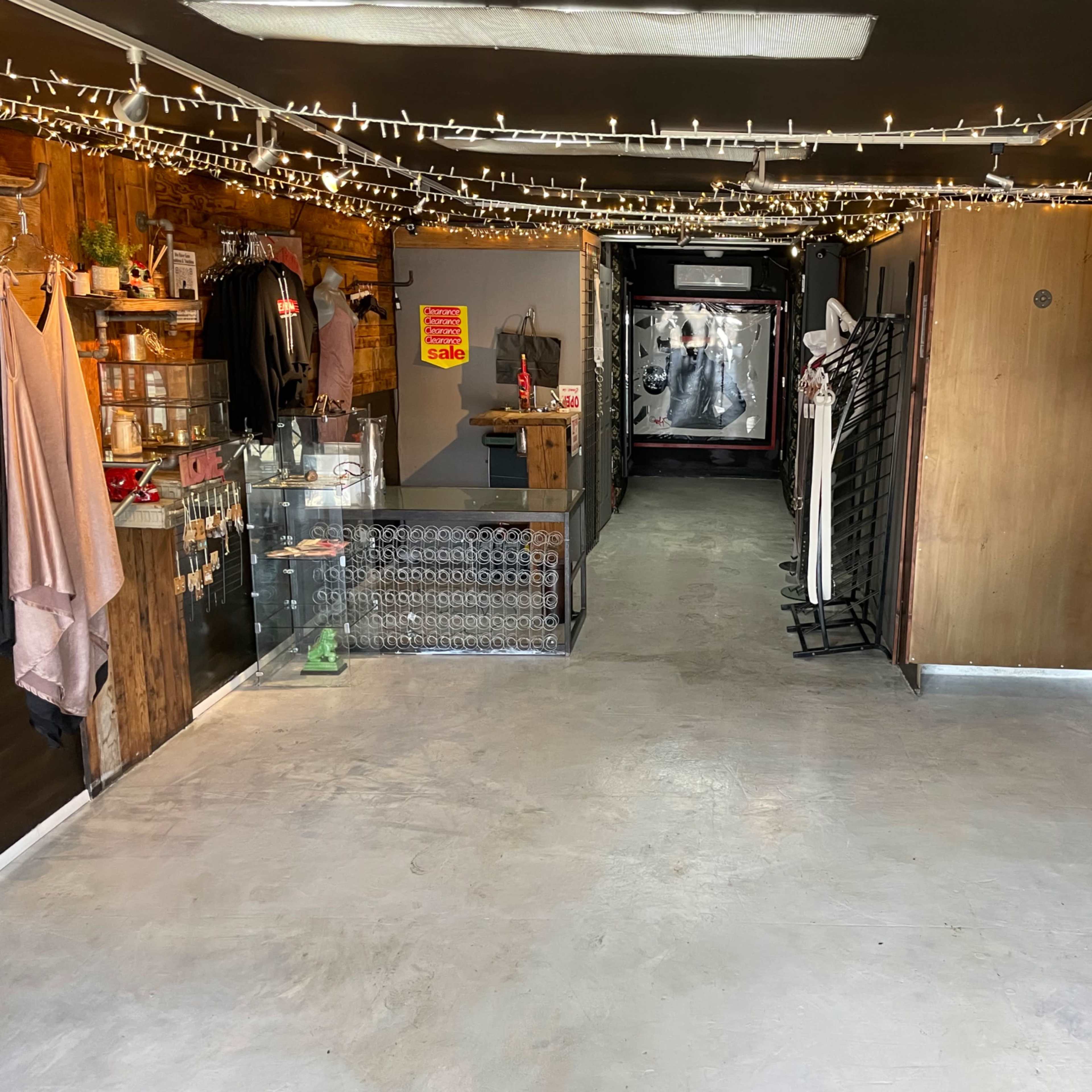 A retail space with clothing displays on the sides, a check-out area, and string lights illuminating the ceiling.