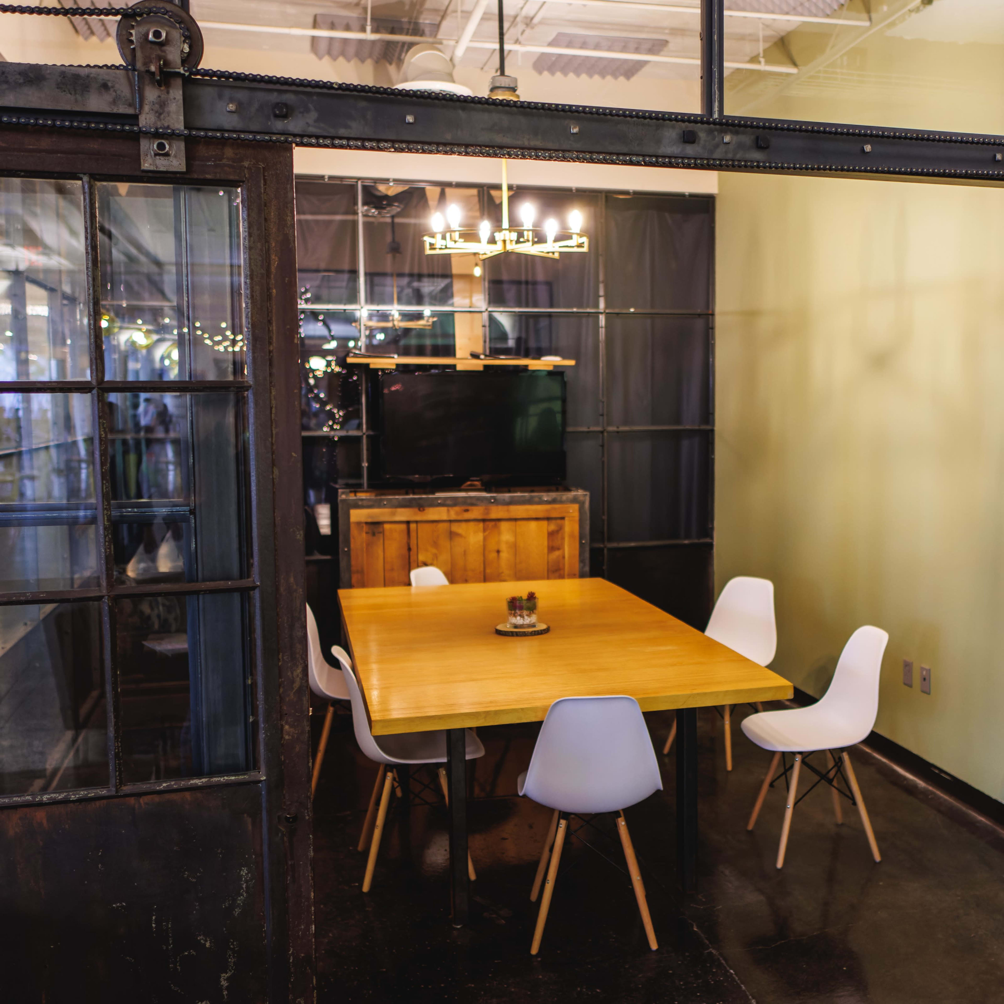 A dining area with a wooden table surrounded by white chairs, located in a room with sliding glass doors.