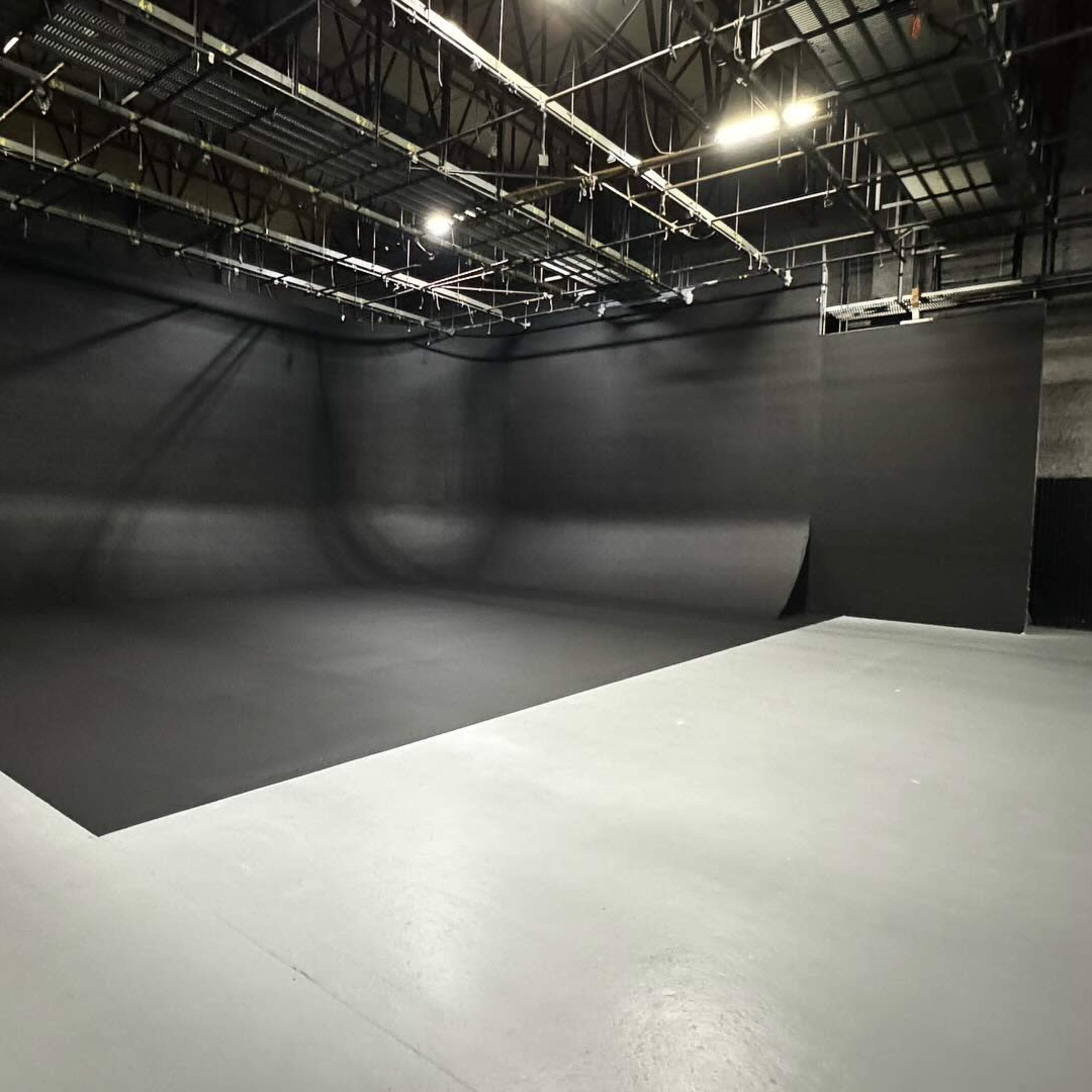 A spacious studio features a large, black backdrop with a smooth, painted floor.