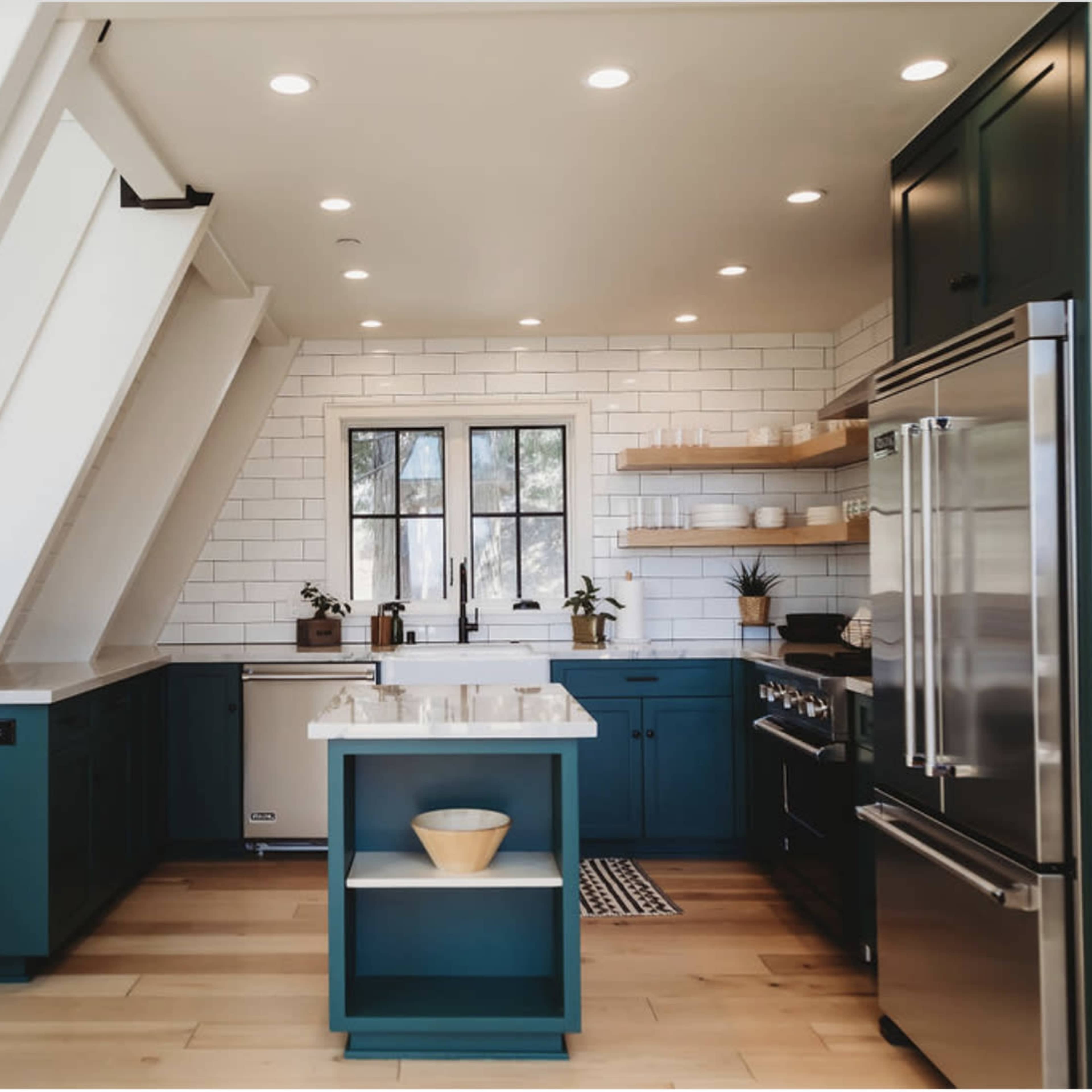 The kitchen features dark blue cabinetry, a white backsplash, and a central island with a white countertop.