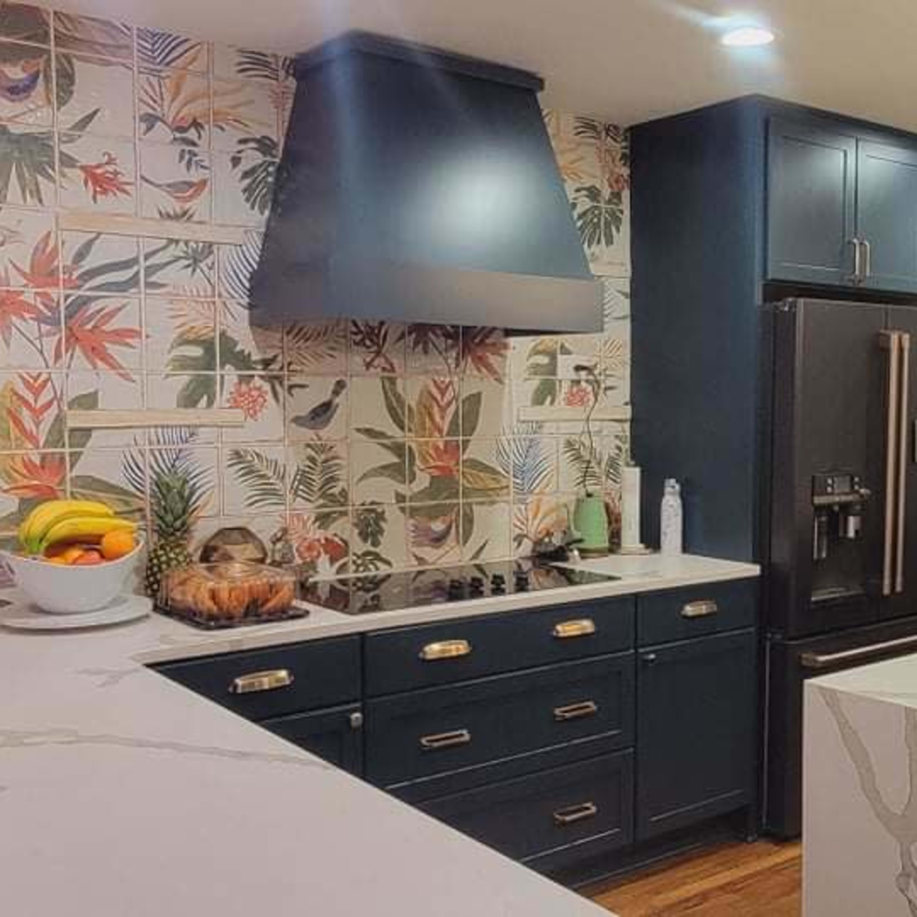 A modern kitchen features dark cabinets, a floral wallpaper backsplash, and a large island with a sink and countertop appliances.