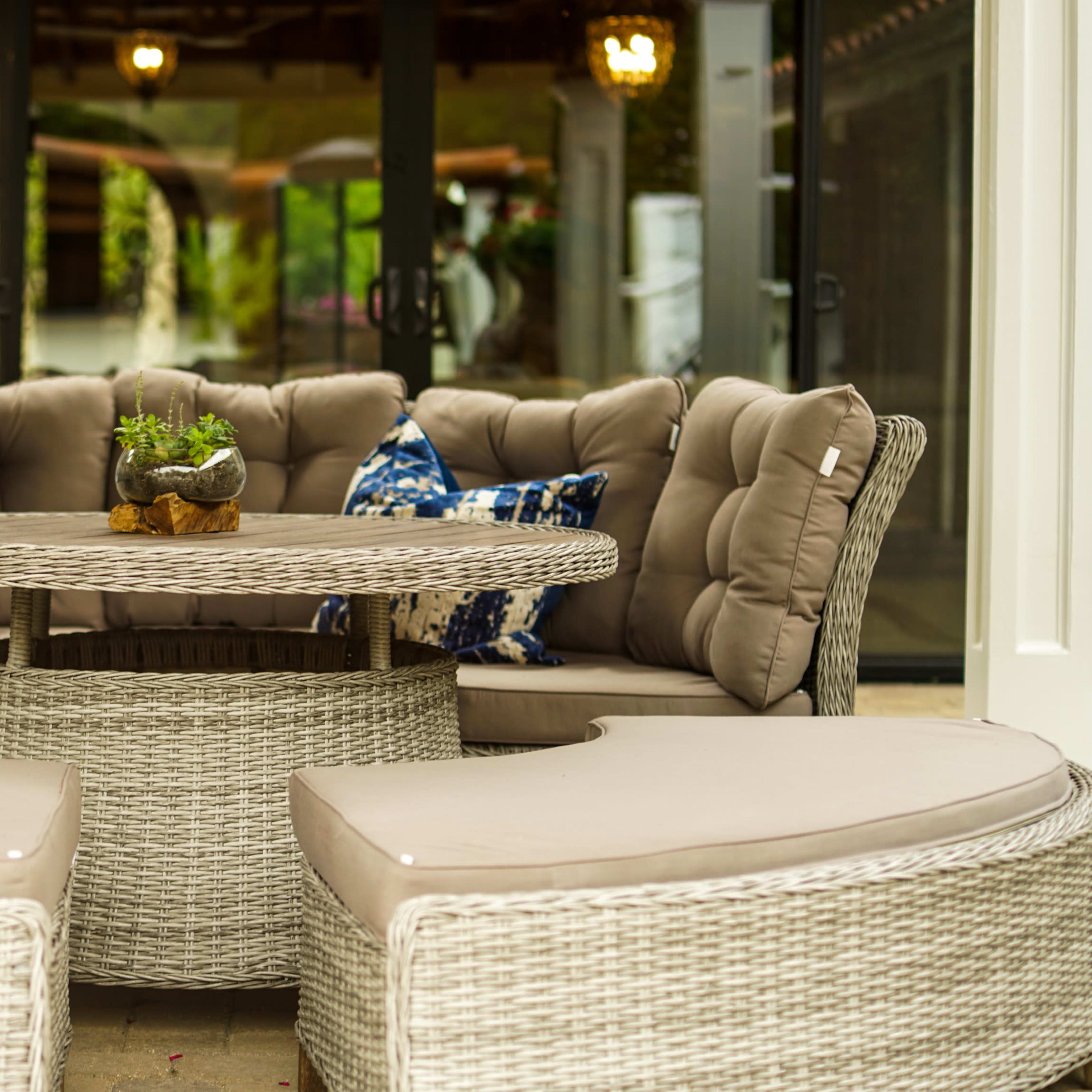 A round outdoor seating arrangement with plush cushions and a matching table surrounded by curved couches.