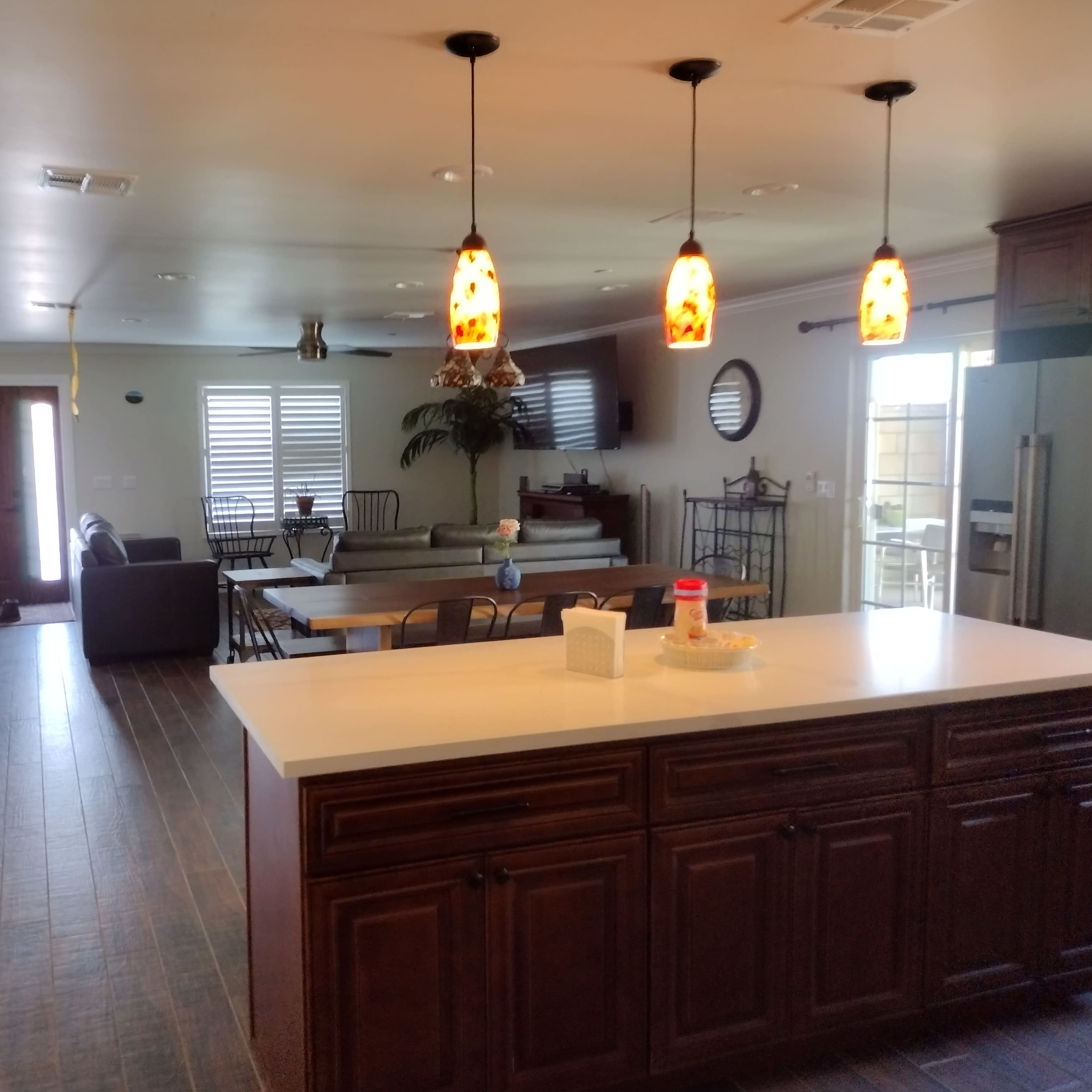 A spacious living and dining area with a kitchen featuring dark wooden cabinets, a large table, and multiple seating arrangements.