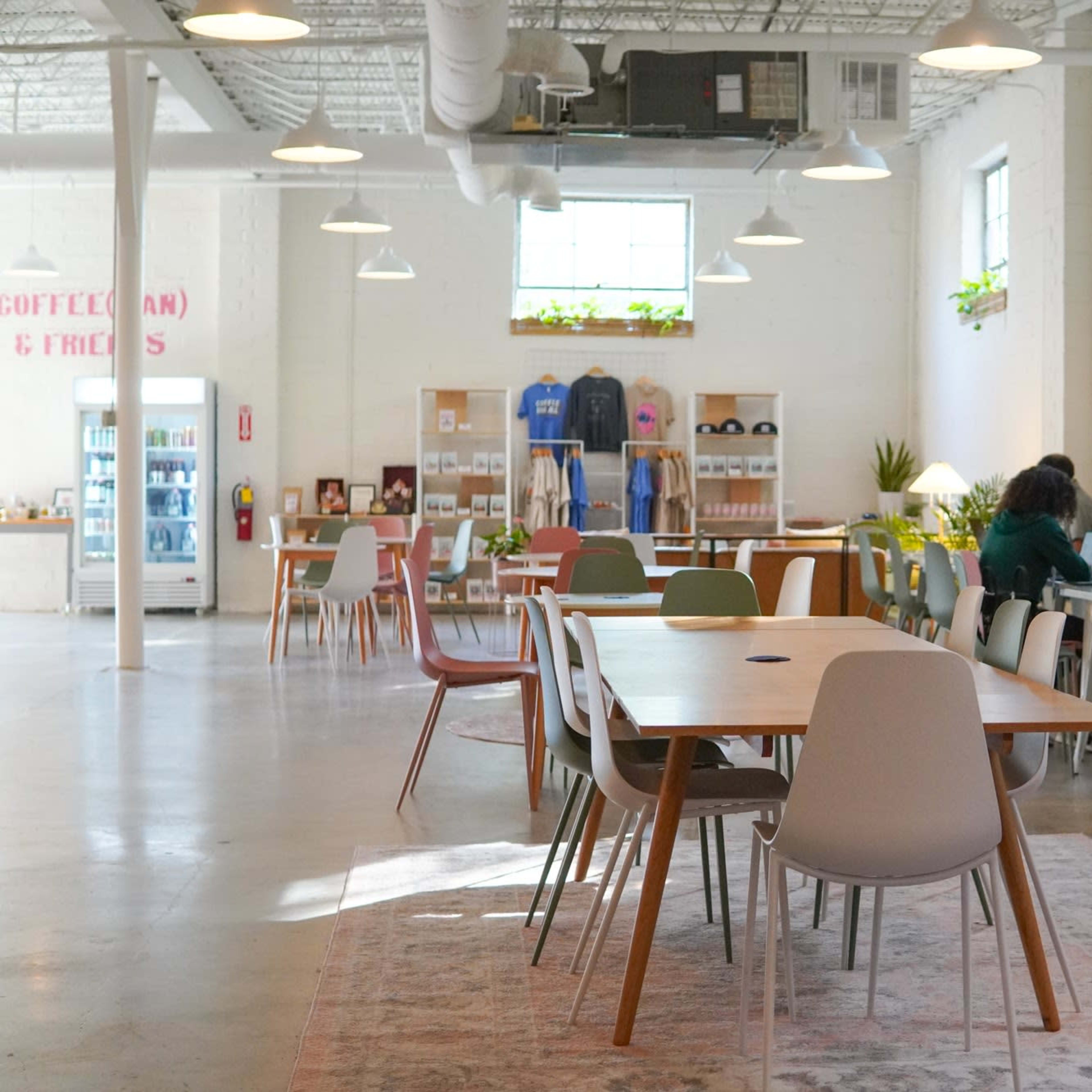A spacious, well-lit café with wooden tables and chairs, where several people are working on laptops and others are engaged in conversation.