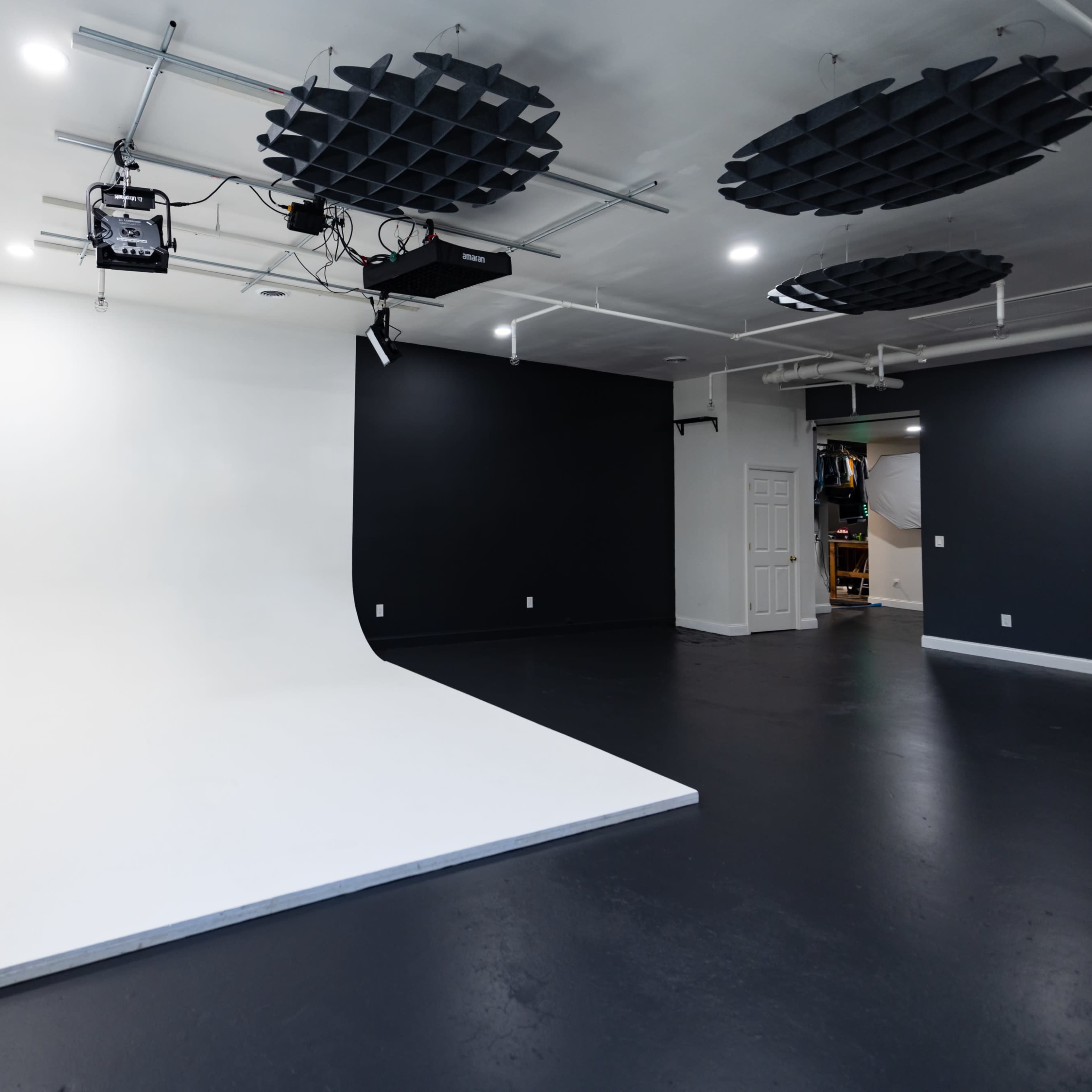 A photography studio featuring a curved white backdrop on one side and dark gray walls on the opposite side.