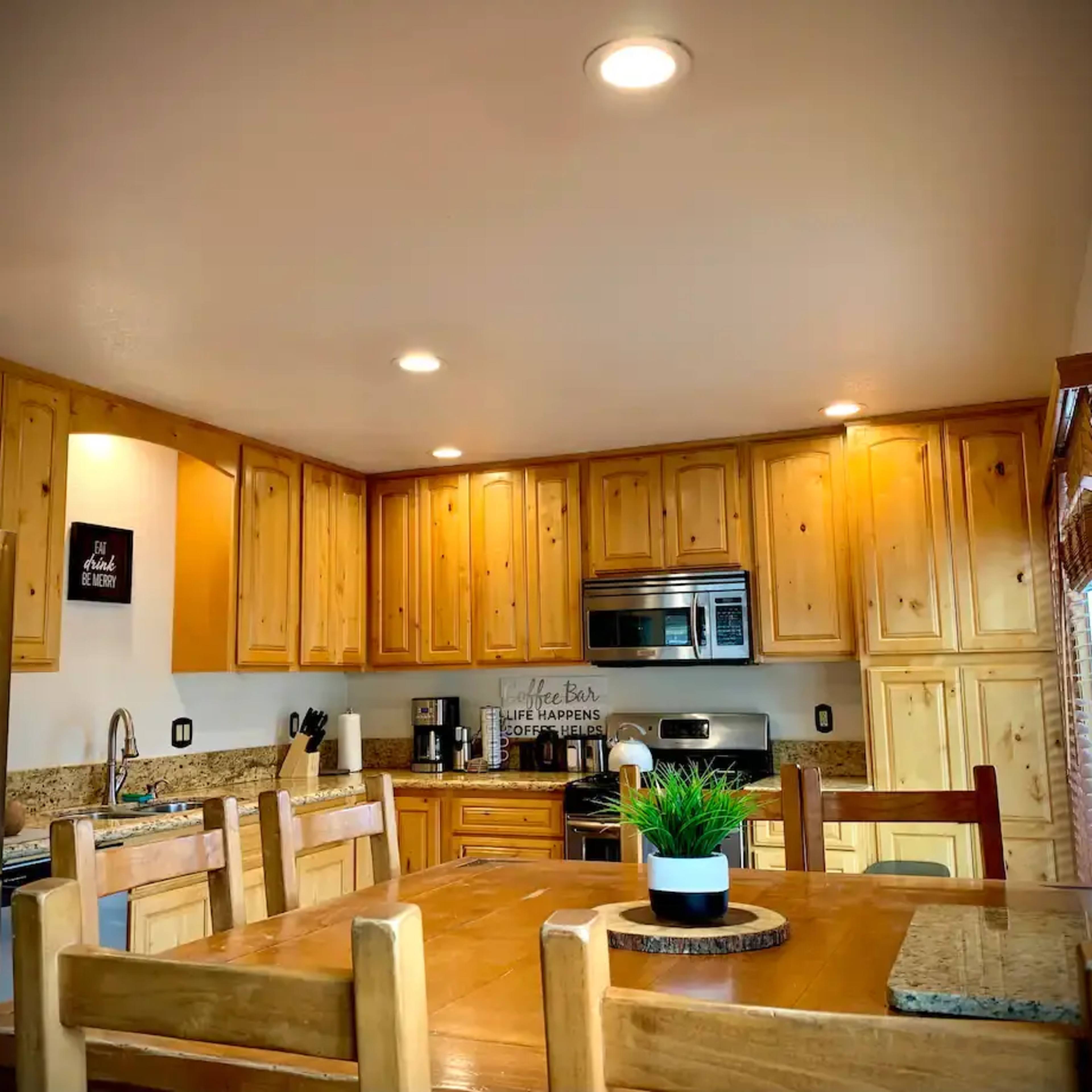 A kitchen with wooden cabinetry, stainless steel appliances, and a dining table set for several people.