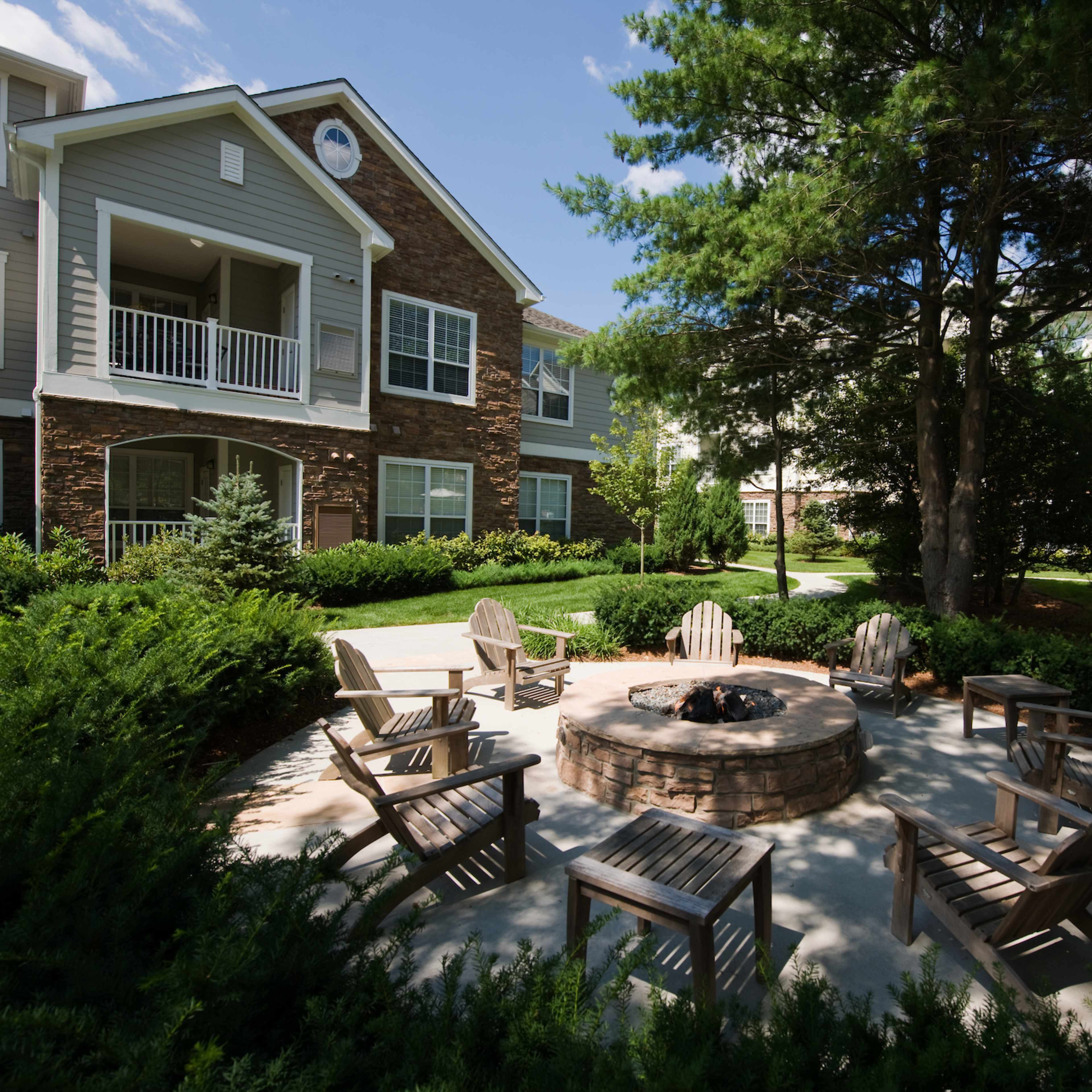 A spacious living area featuring a dining table, a comfortable seating arrangement, large windows, and a stone fireplace.